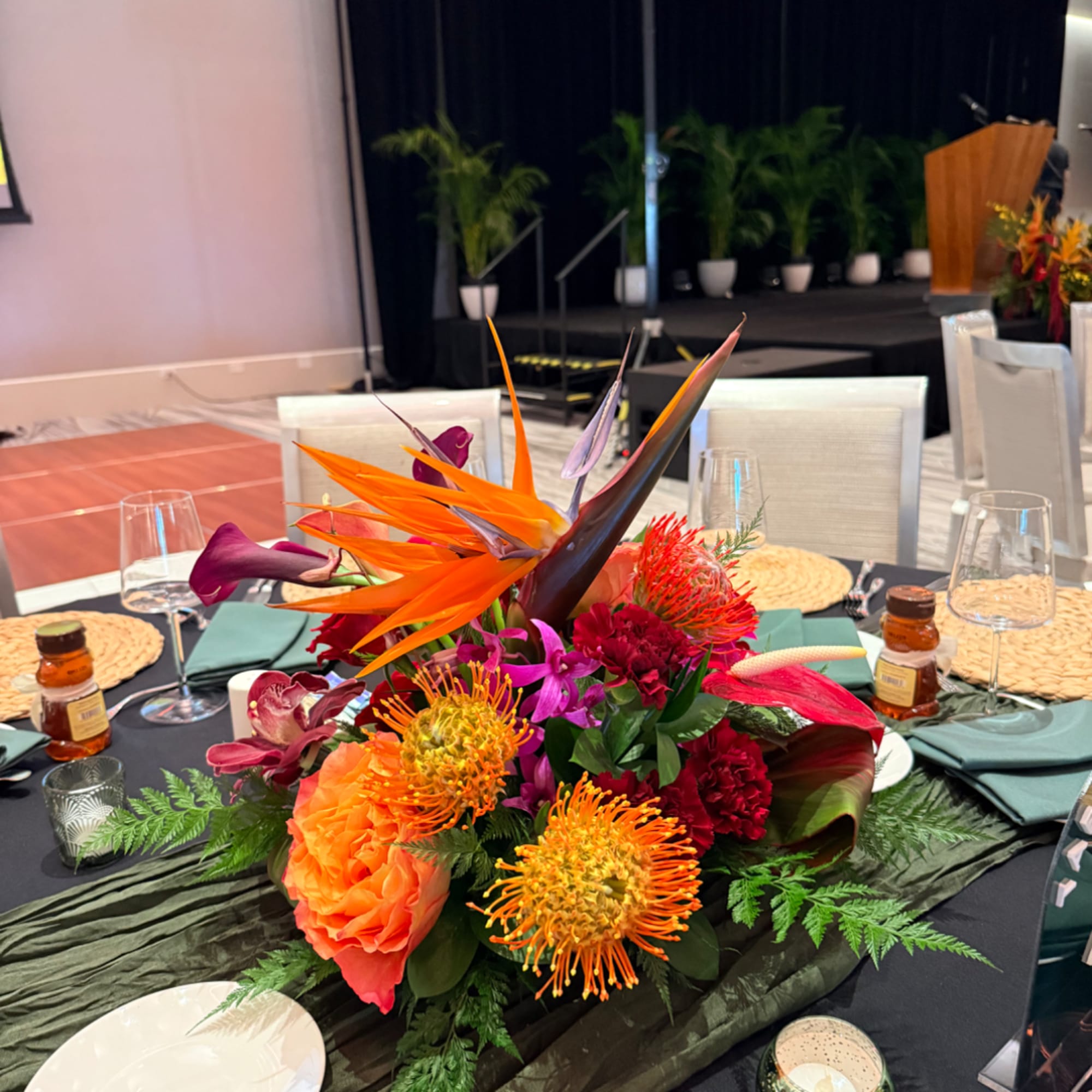 Tropical centerpiece with orange bird of paradise and bright mixed flowers on a table