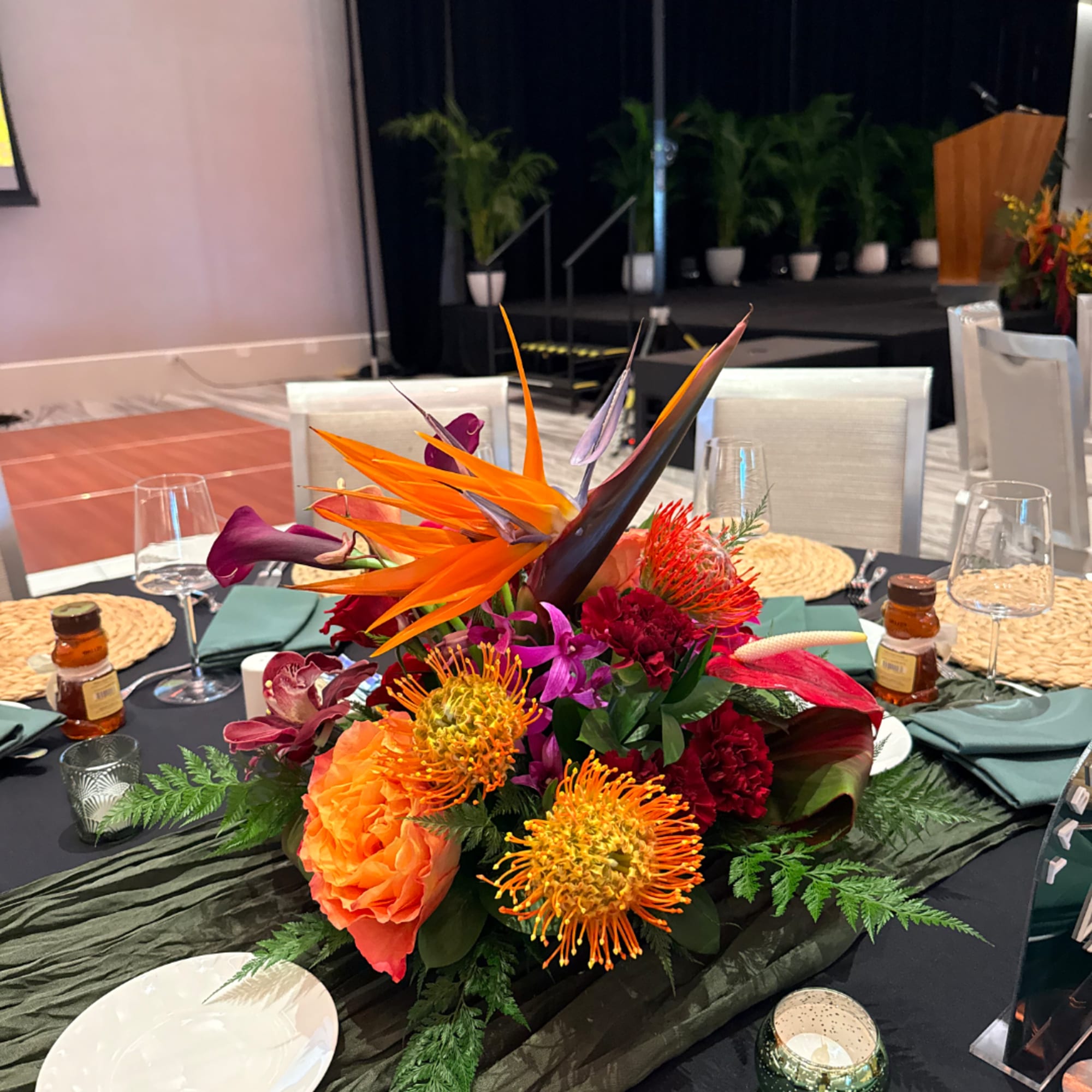 Tropical floral centerpiece with orange and purple blooms on a banquet table
