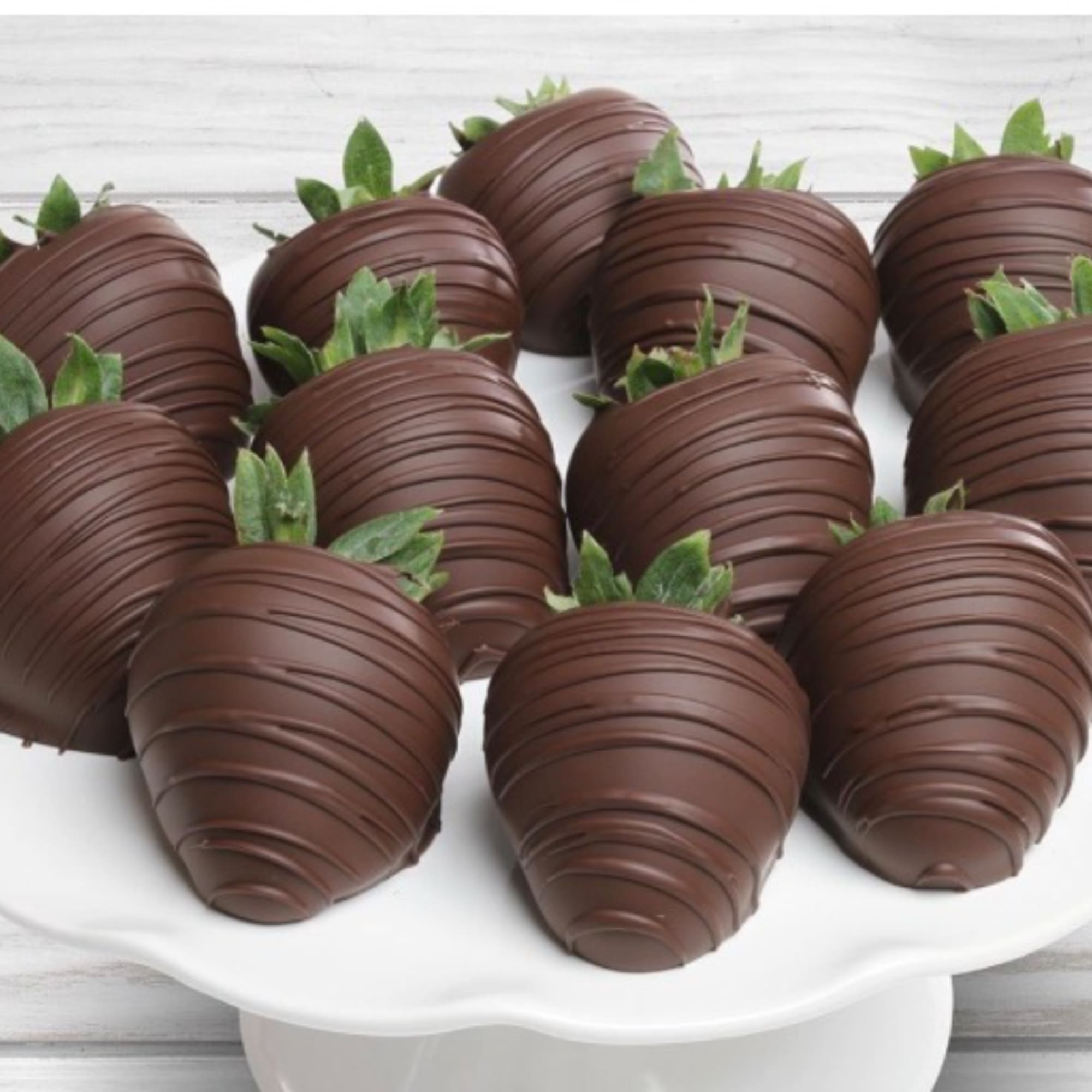Chocolate-covered strawberries arranged on a white pedestal stand