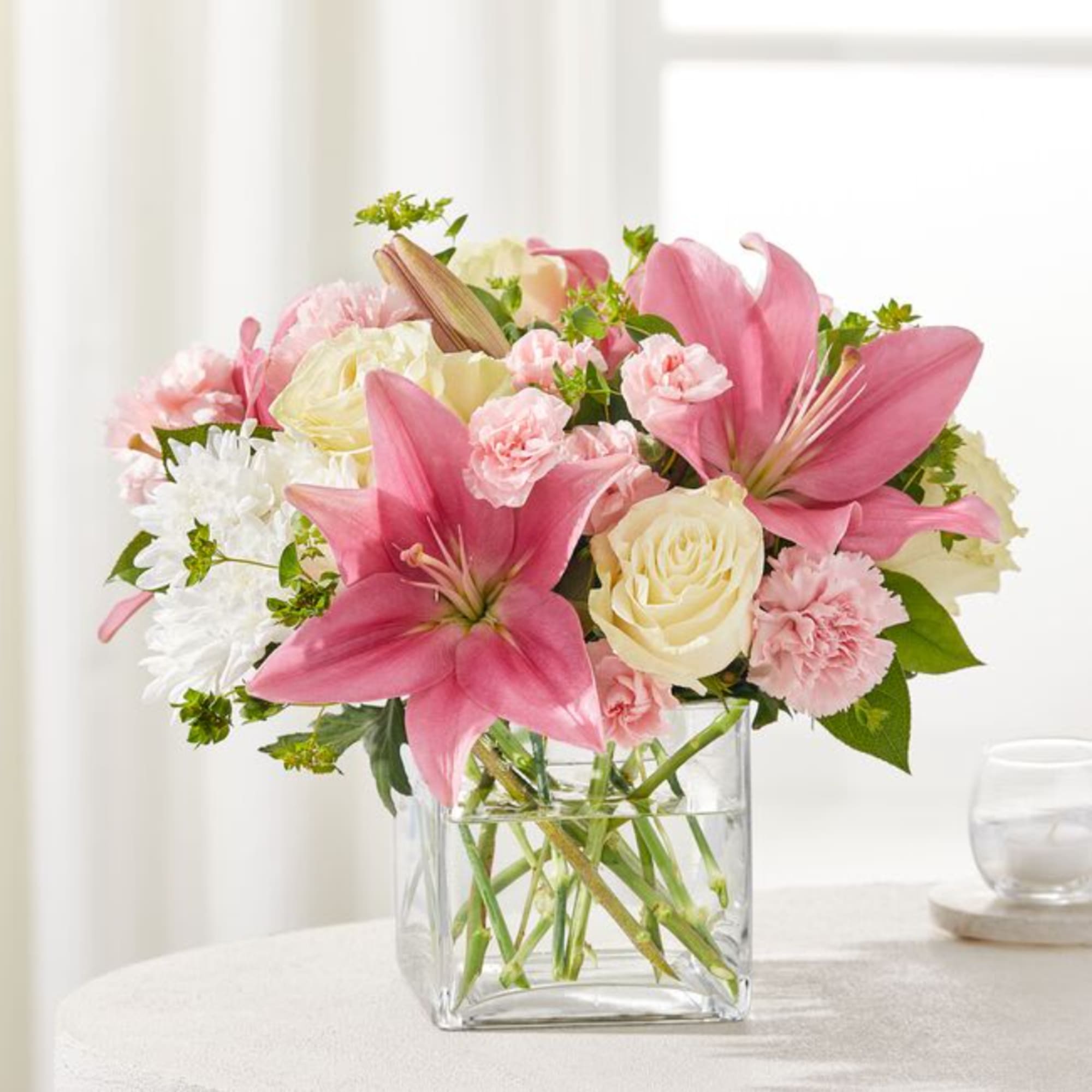 Pink lilies and cream roses in a clear glass vase