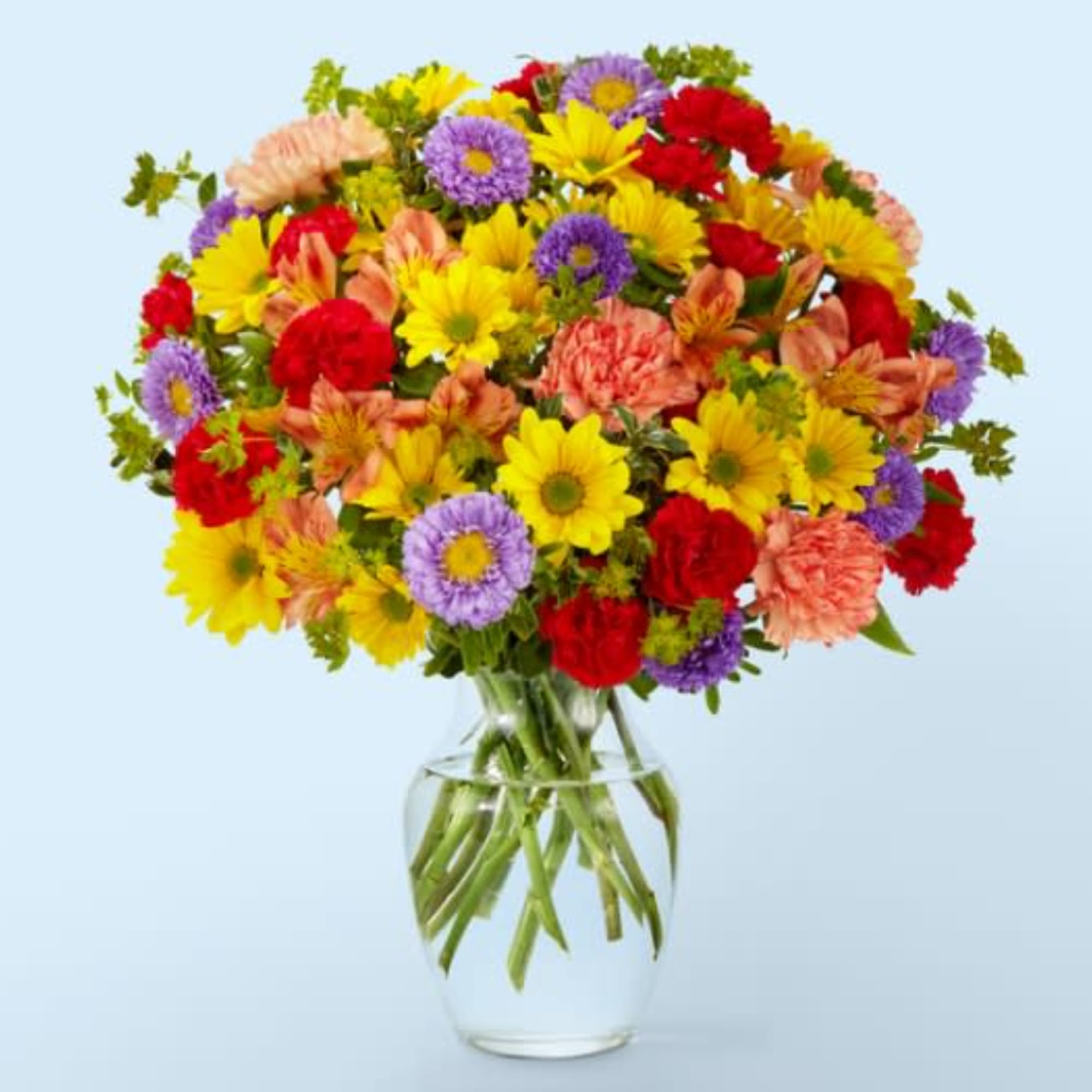 Mixed bouquet of daisies, carnations, and asters in a clear glass vase