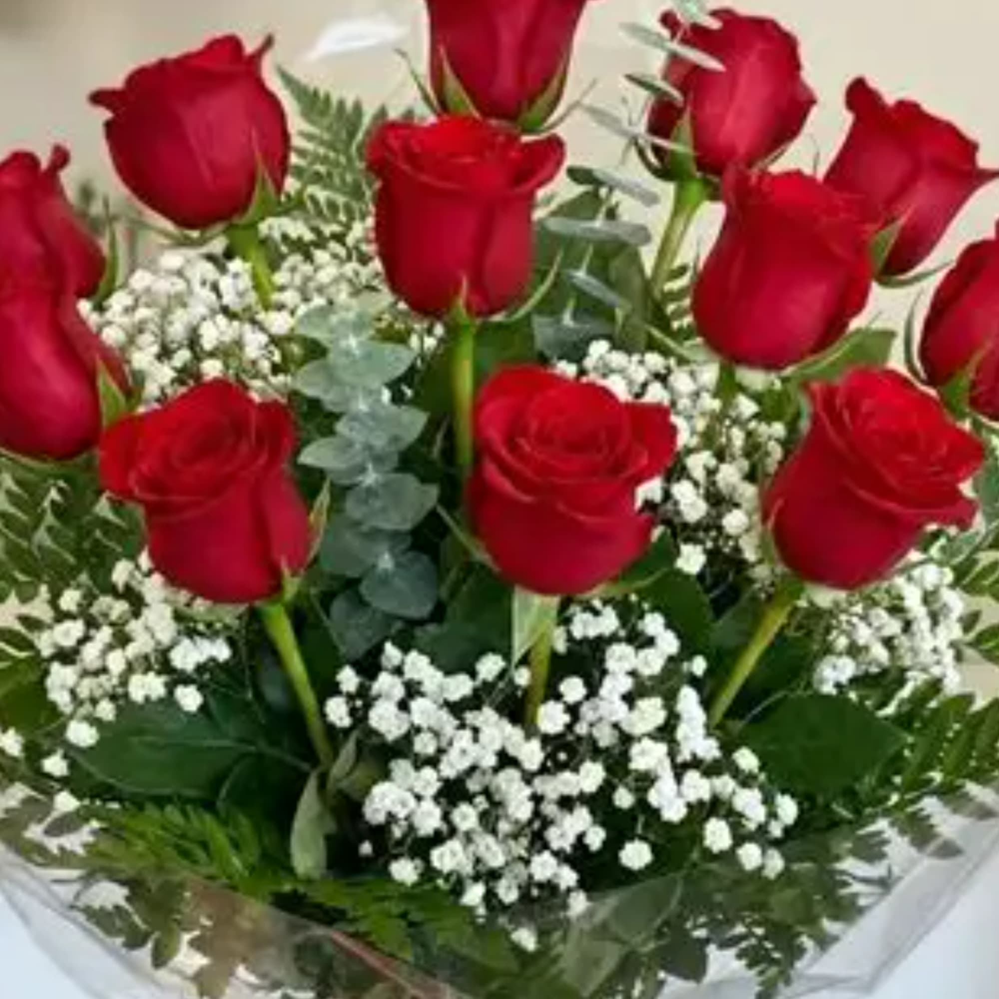 A clustered bouquet of long-stem red roses wrapped in clear floral wrap