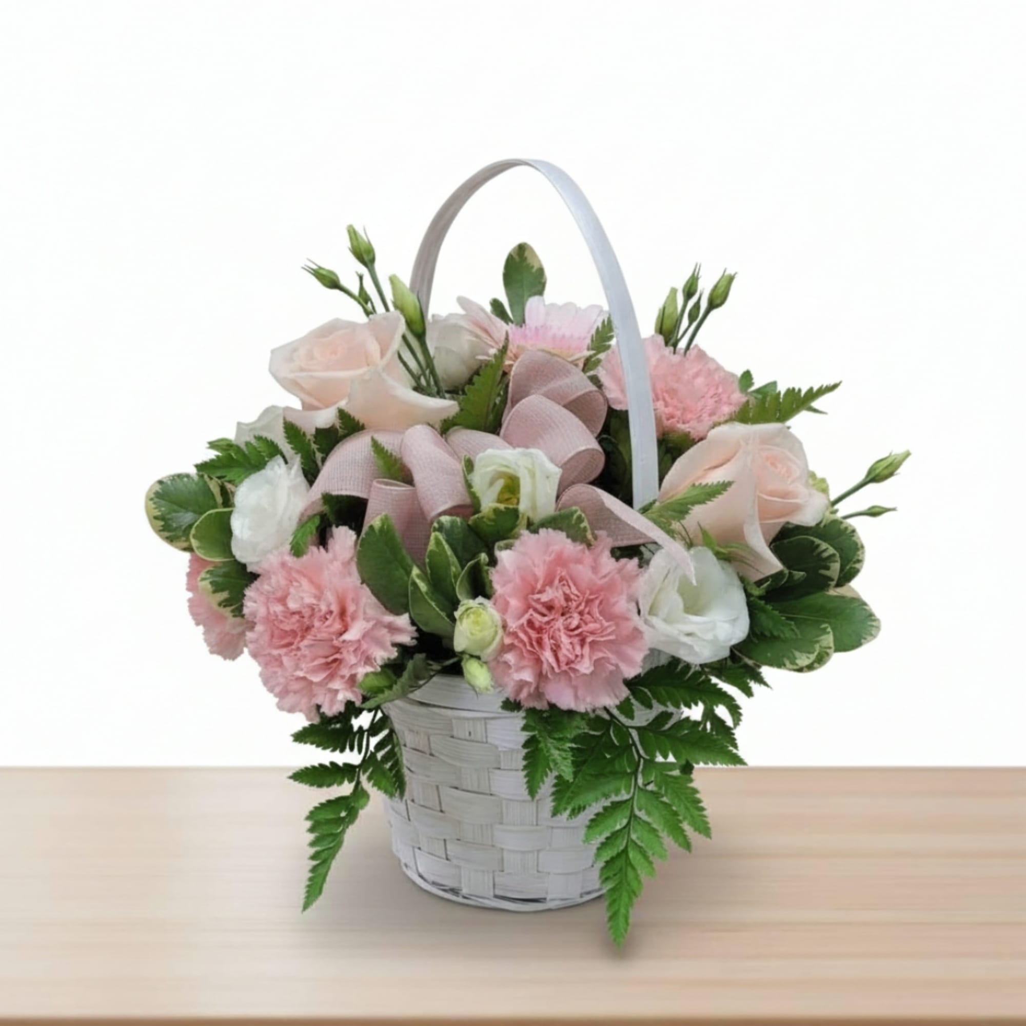Pink and white flowers arranged in a white basket with a ribbon handle