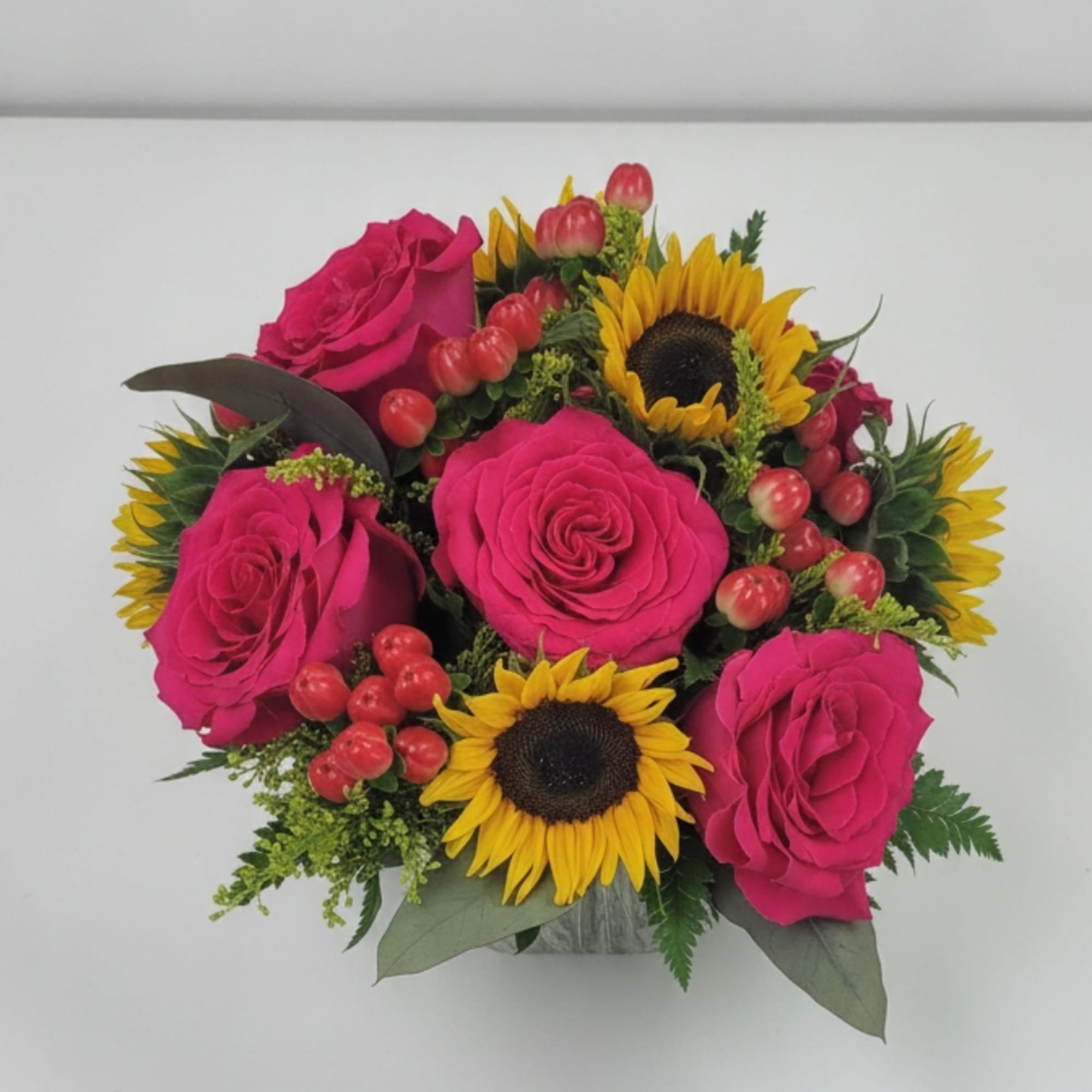 Pink roses and sunflowers arranged in a small vase