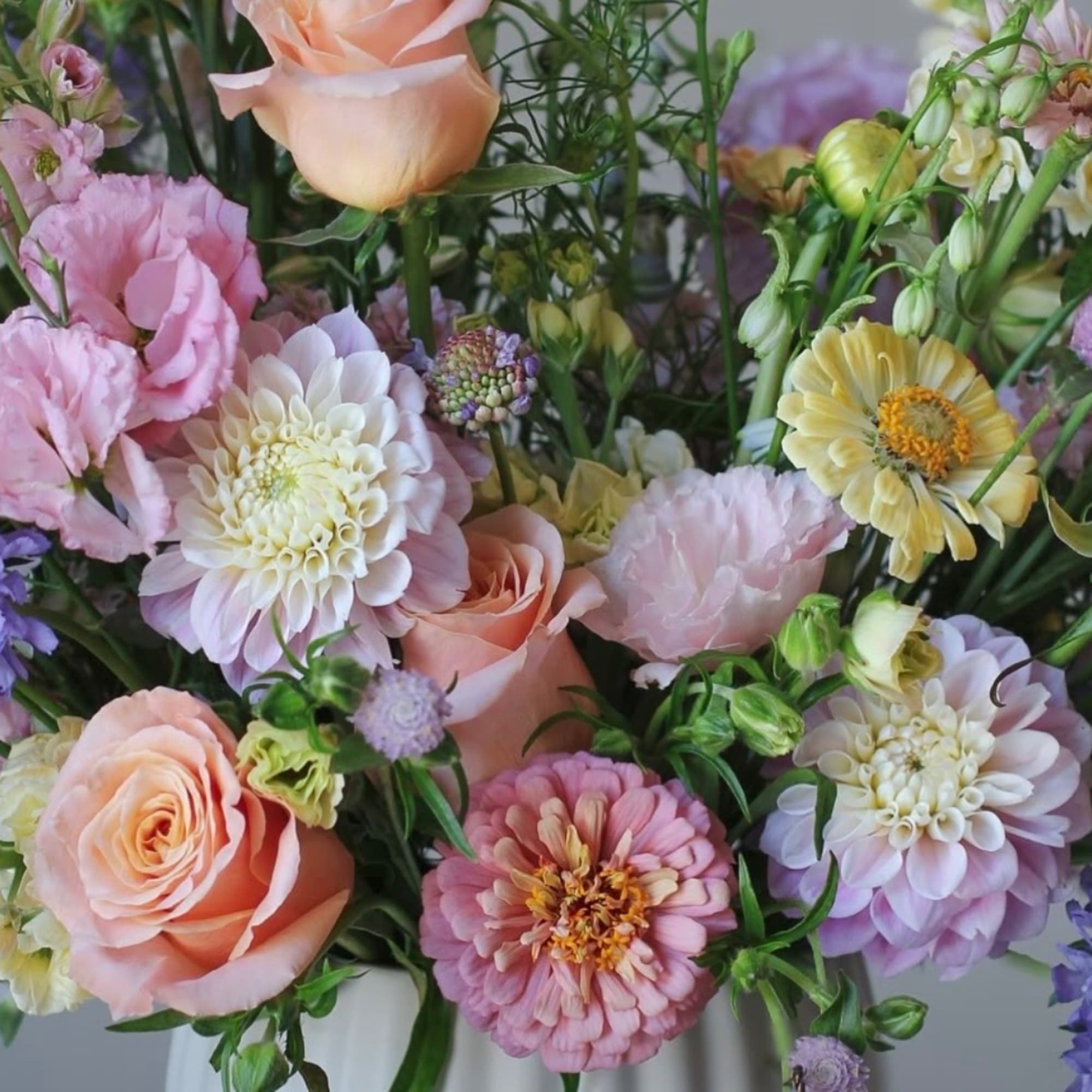 Pastel bouquet of roses, dahlias, and mixed blooms in a vase