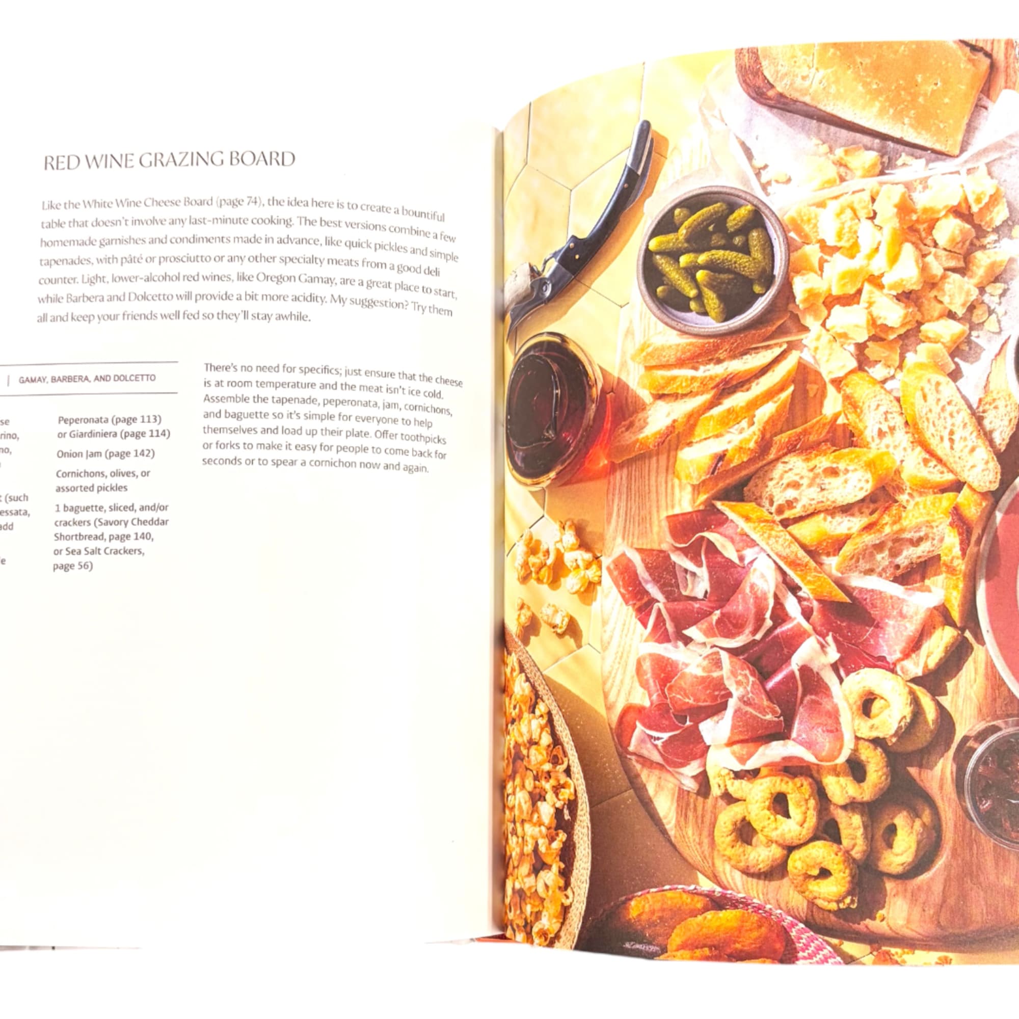 Open cookbook page showing a red wine grazing board with meats, cheese, and pickles