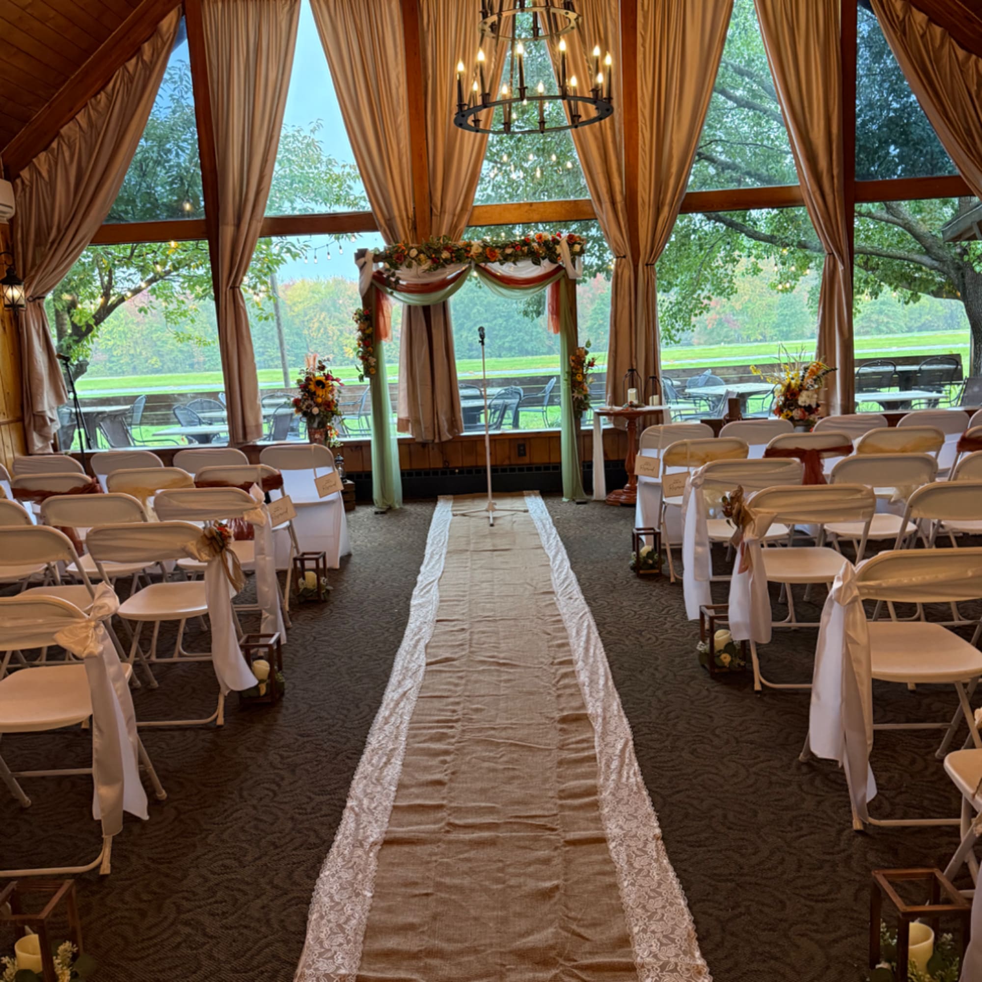 Wedding ceremony aisle with floral arch and decorated chairs in a bright hall