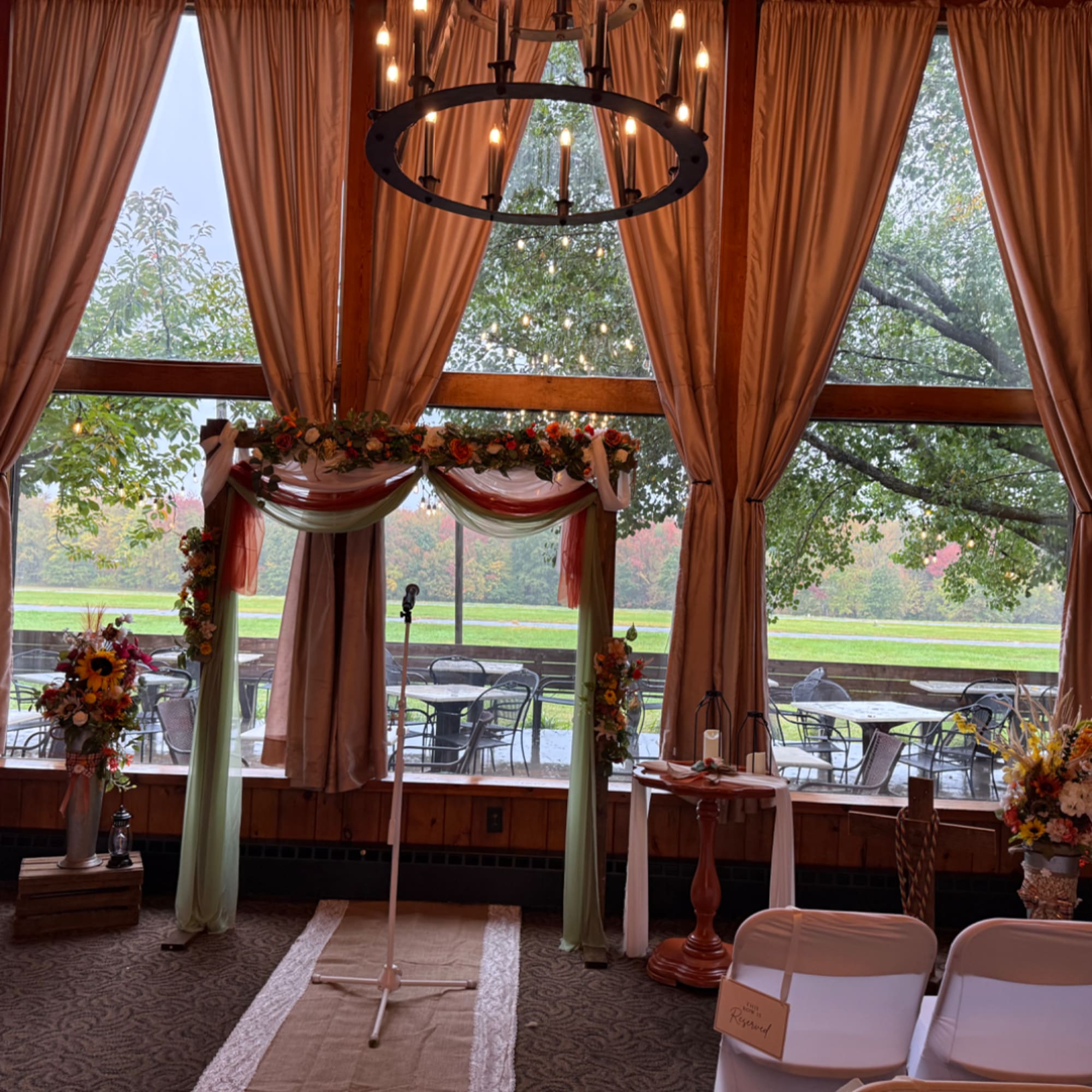 Wedding arch with floral garland and draped fabric in front of large windows