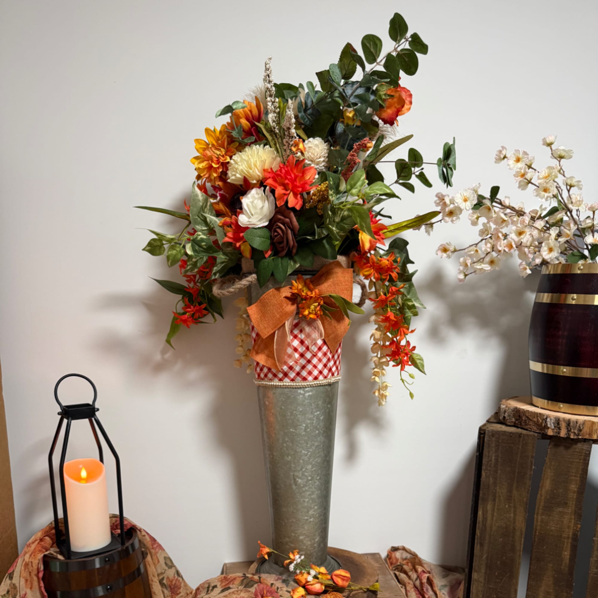 Tall autumn floral arrangement in a metal vase with orange and white blooms