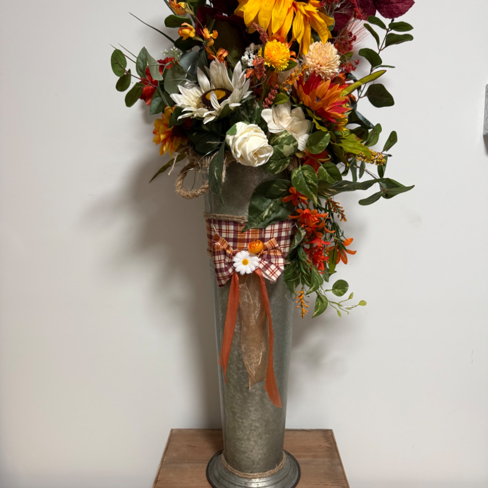 Tall autumn floral arrangement in a metal vase with plaid ribbon