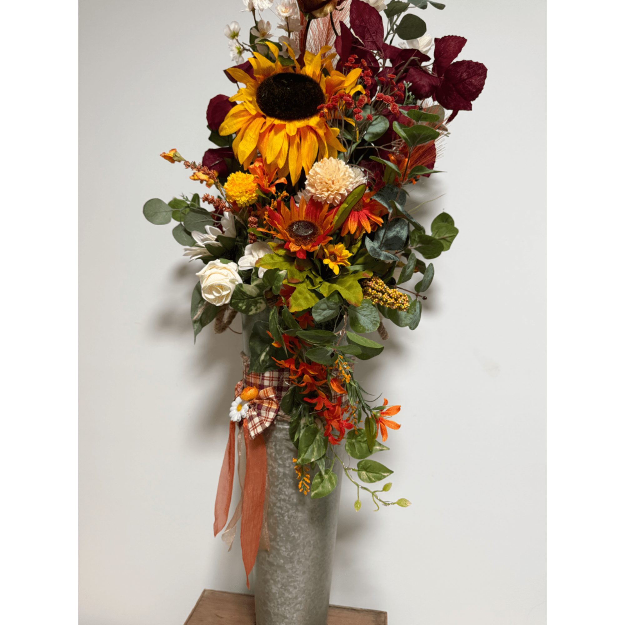 Tall autumn floral arrangement in a silver vase with sunflowers and orange blooms