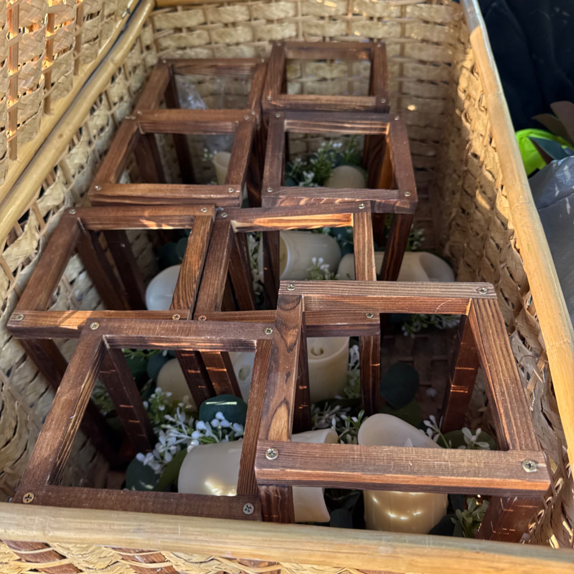 Wooden lantern frames in a wicker basket with small floral accents