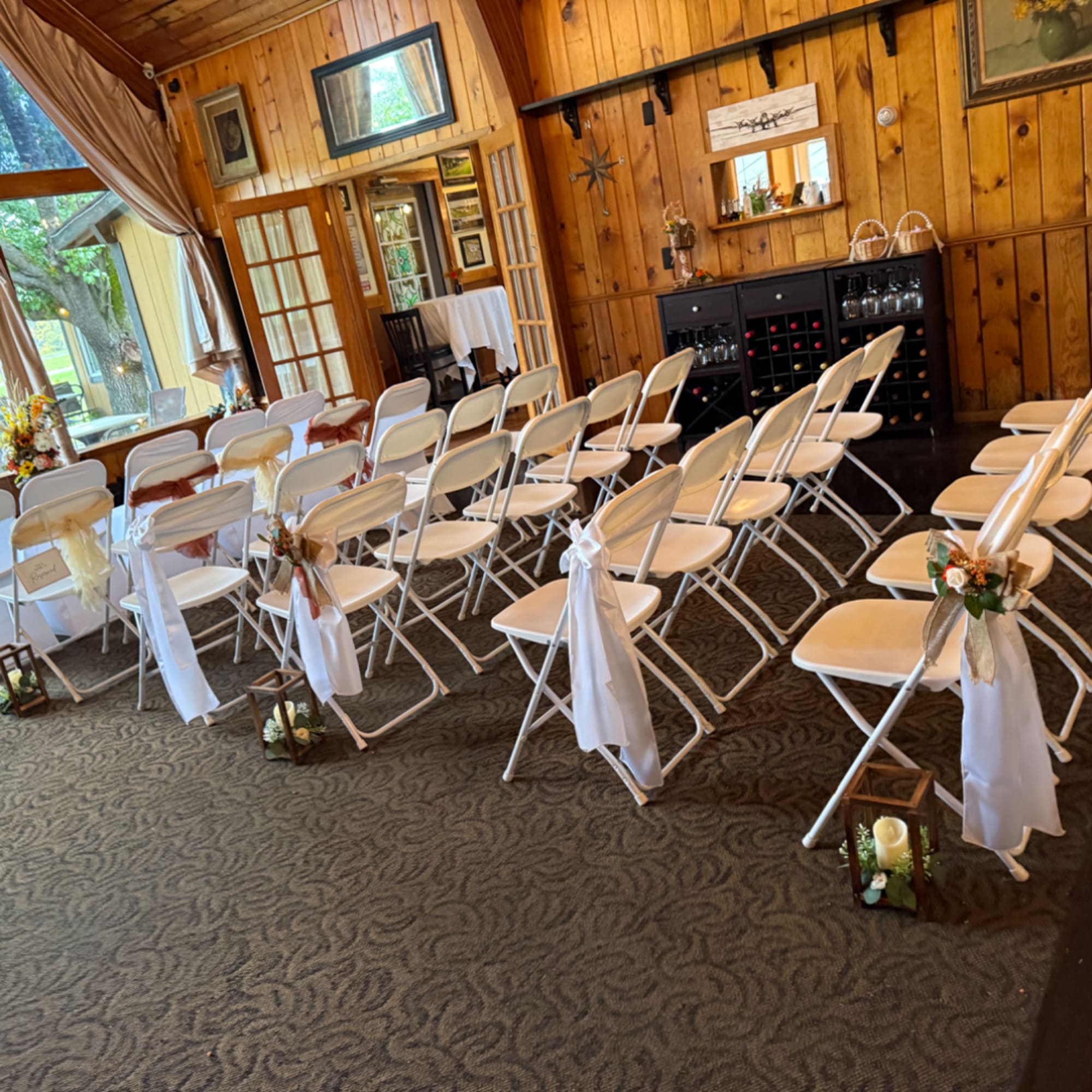 White chairs decorated with ribbons and small floral accents in a rustic room