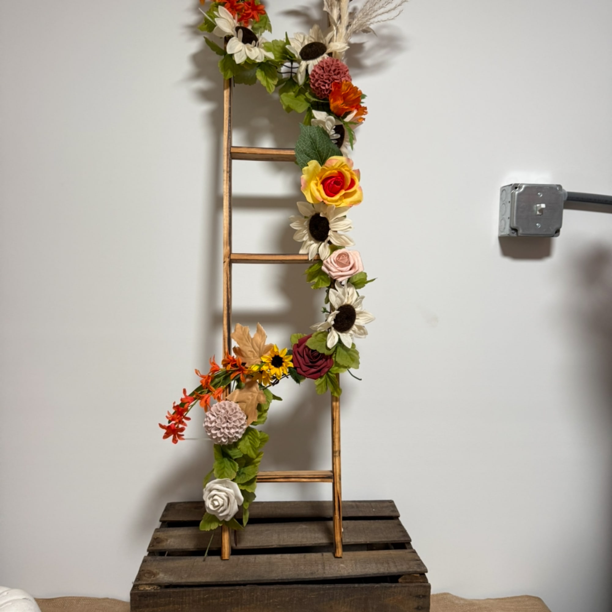 Floral garland wrapped around a wooden ladder display