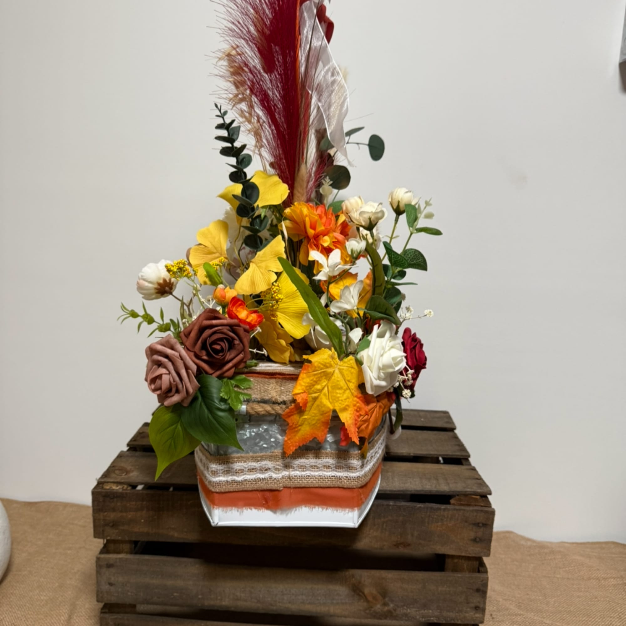 Autumn floral arrangement with roses and yellow blooms in a wrapped container
