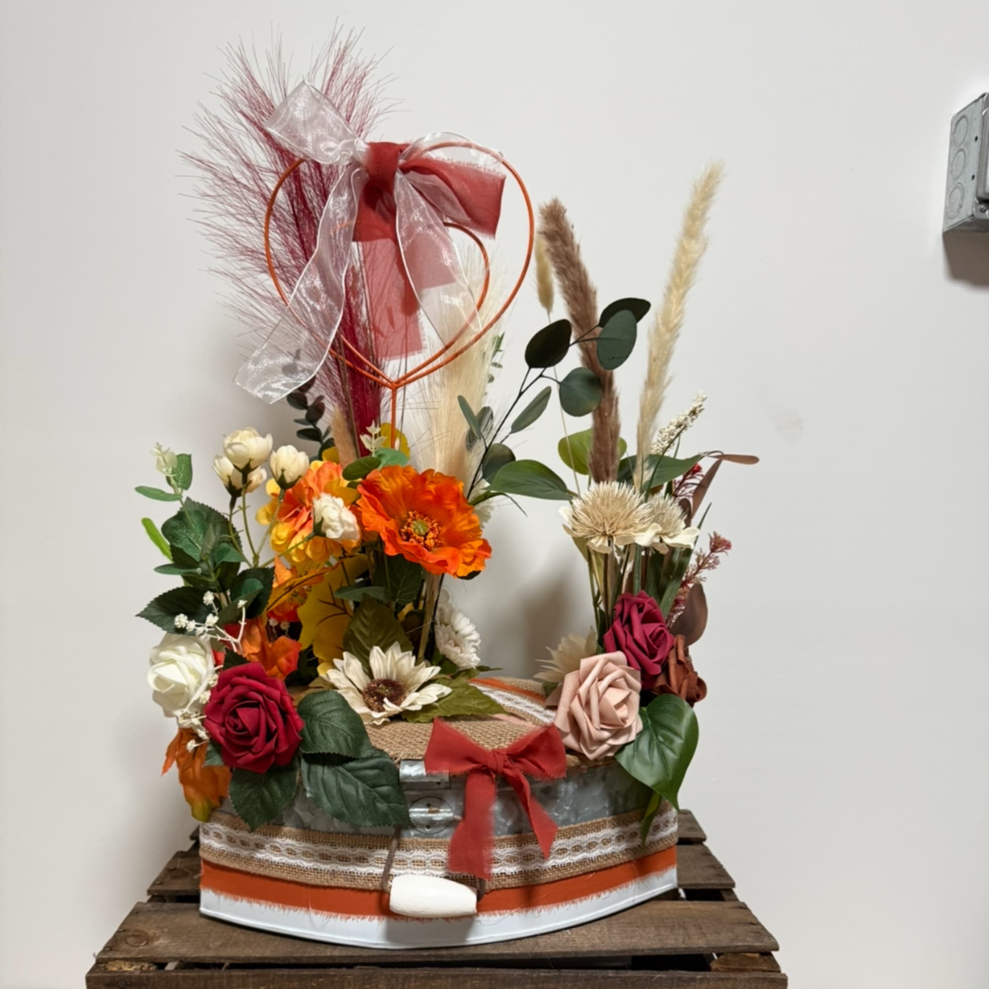Floral arrangement in a decorated box with roses and dried grasses