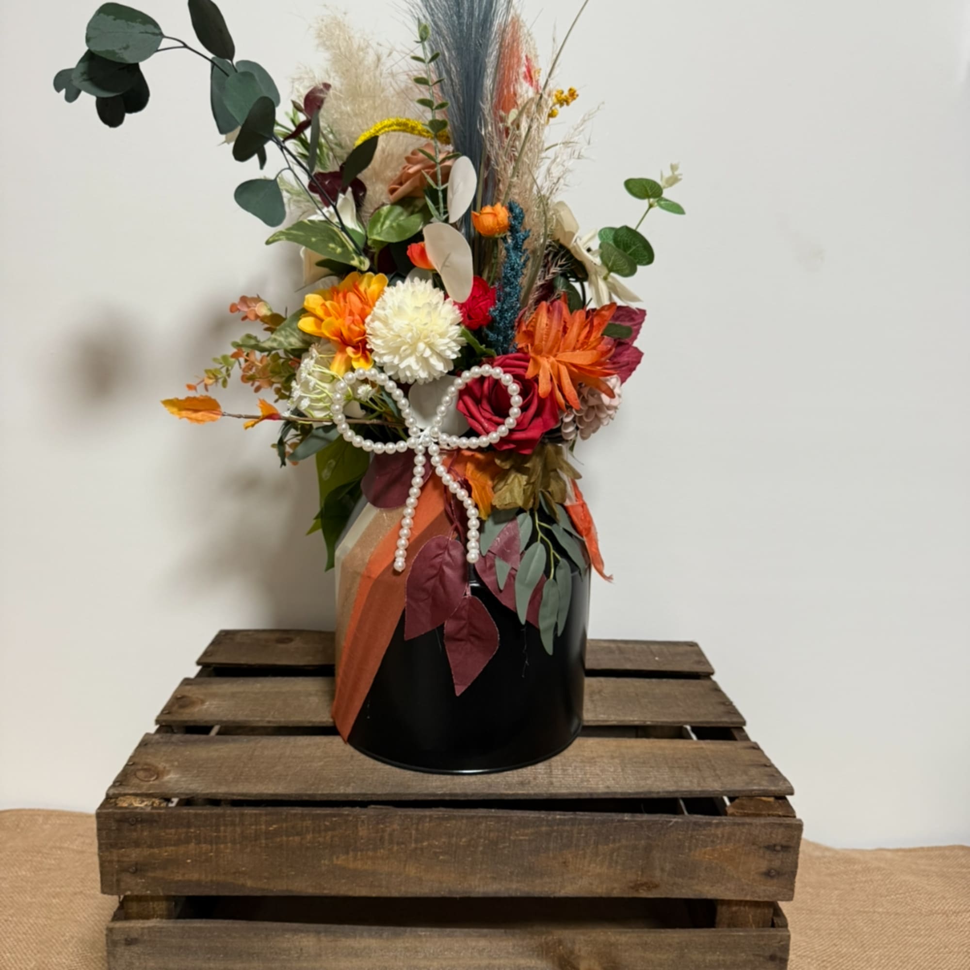 Colorful floral arrangement in a black vase with a pearl bow