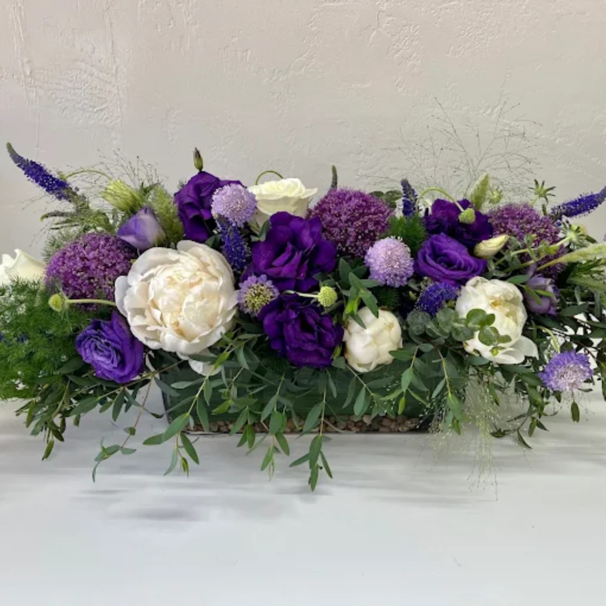 Purple and white floral arrangement in a low rectangular container