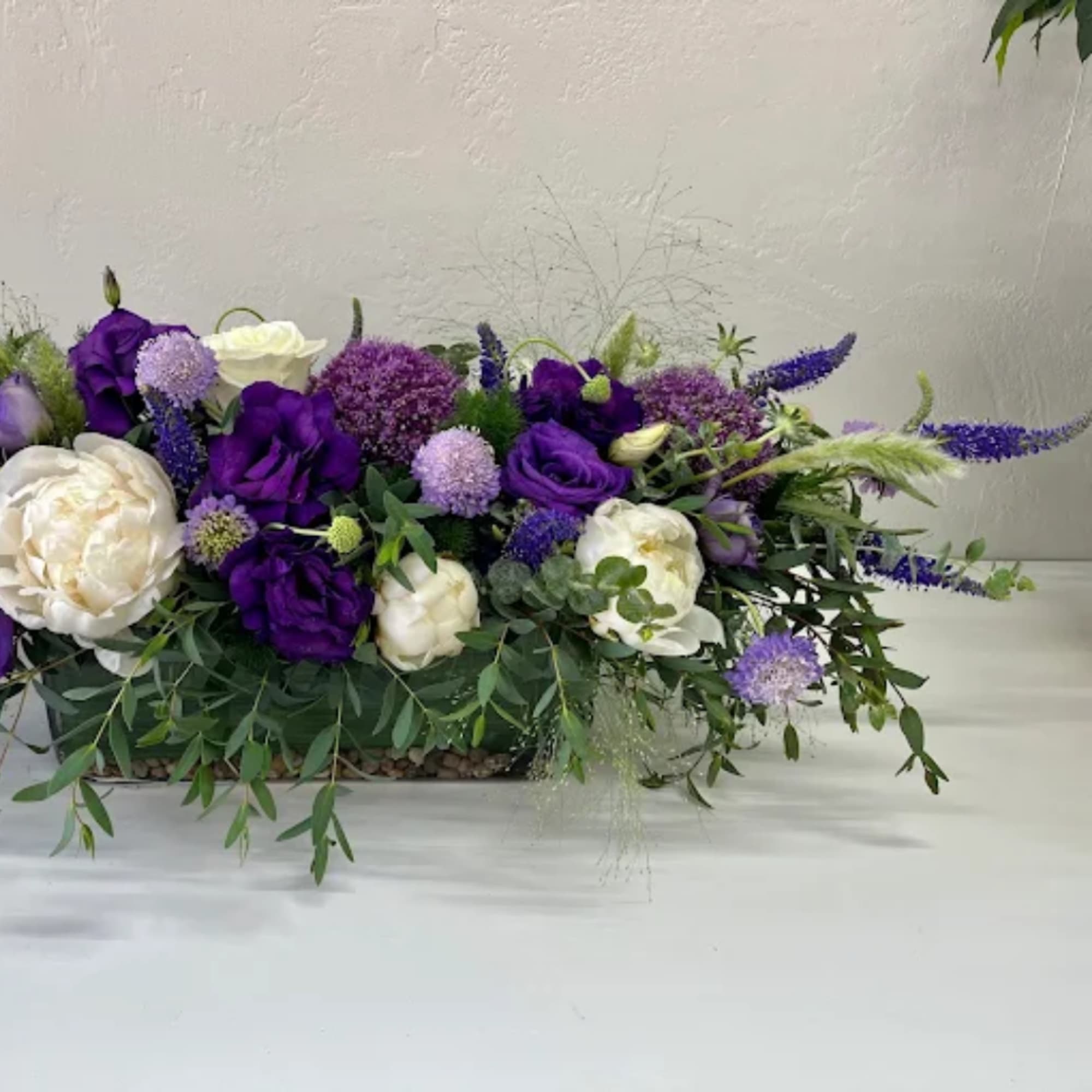 Purple and white floral centerpiece in a low rectangular container