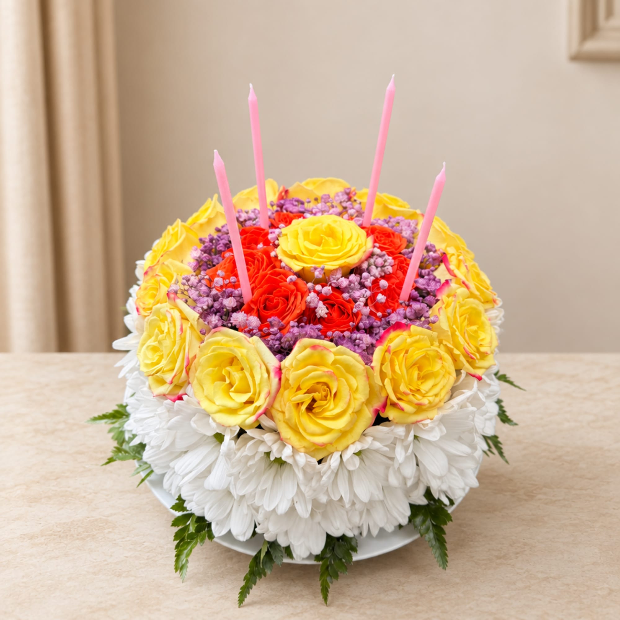Round floral cake with yellow and red roses and pink candles