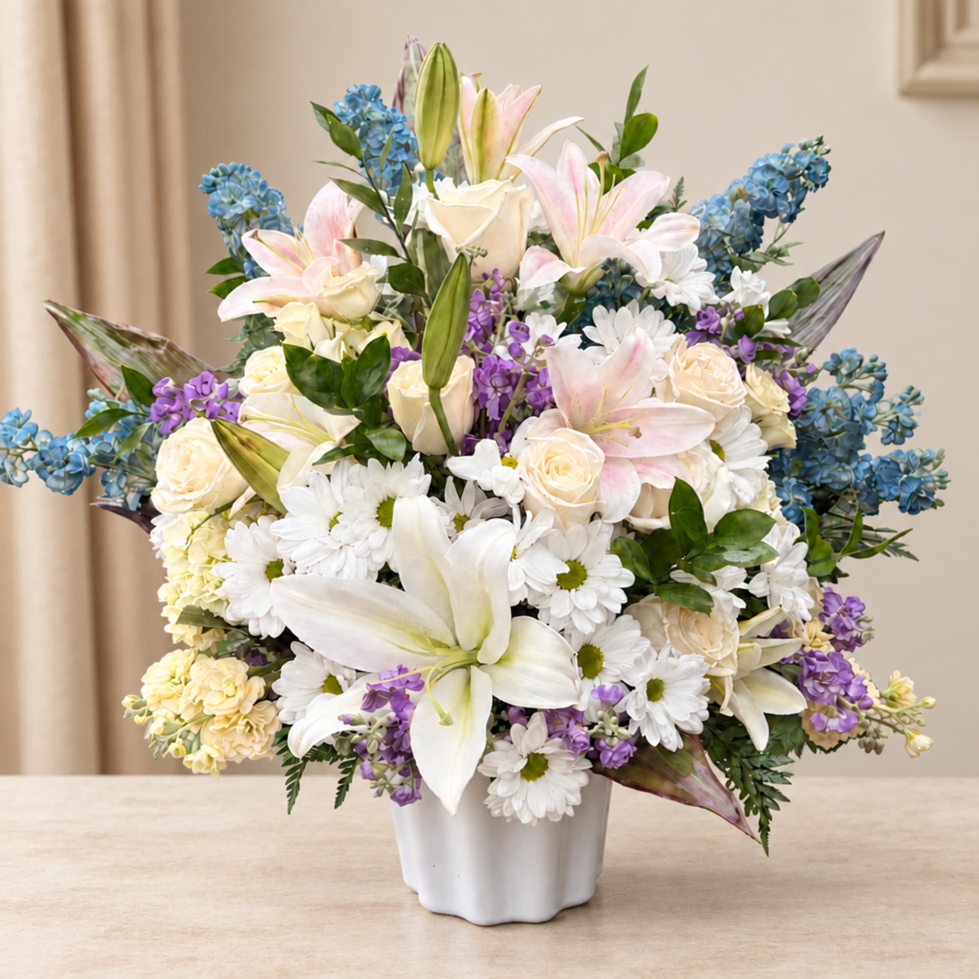 Mixed bouquet of lilies, roses, and daisies in a white vase