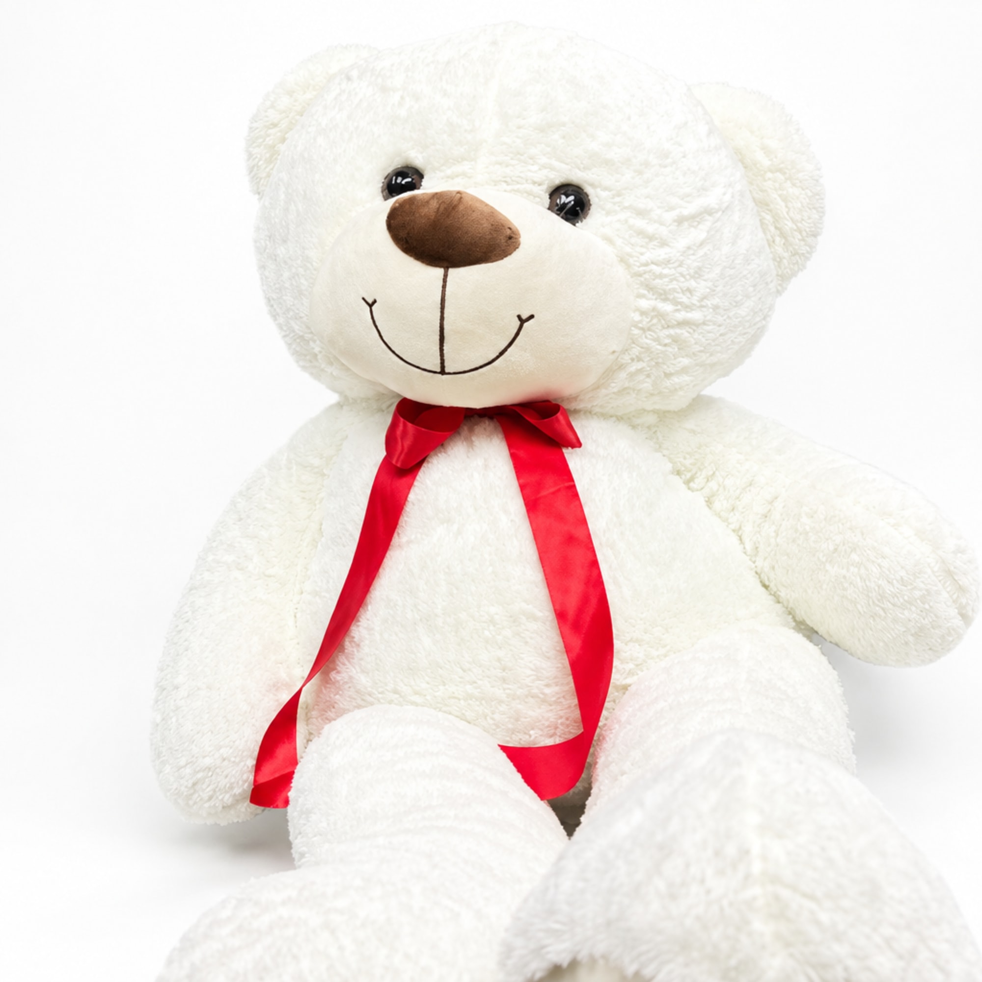 White teddy bear with a red ribbon bow