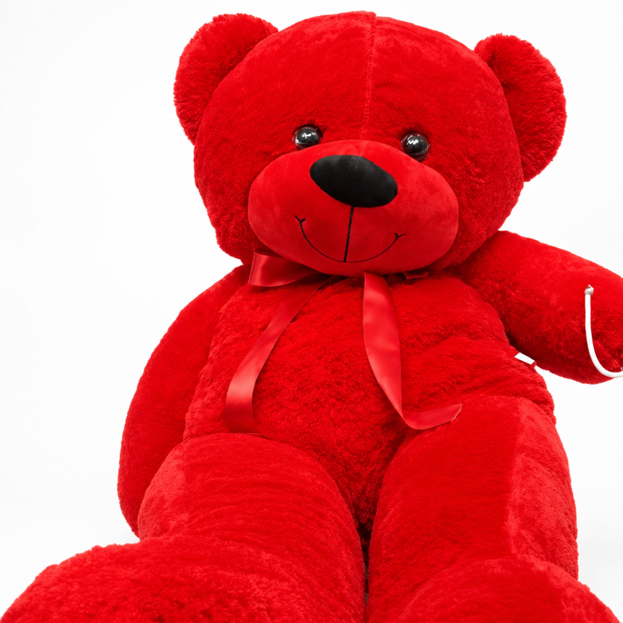 Large red teddy bear with a ribbon bow on a white background