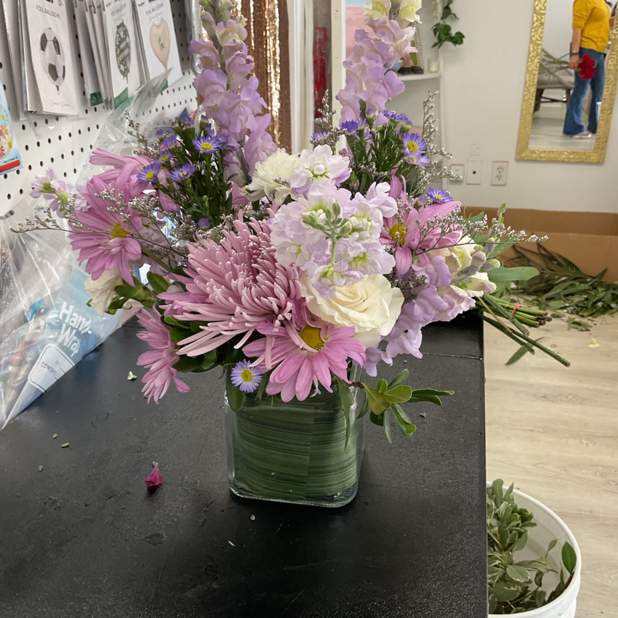 Mixed pink and lavender flowers arranged in a square glass vase