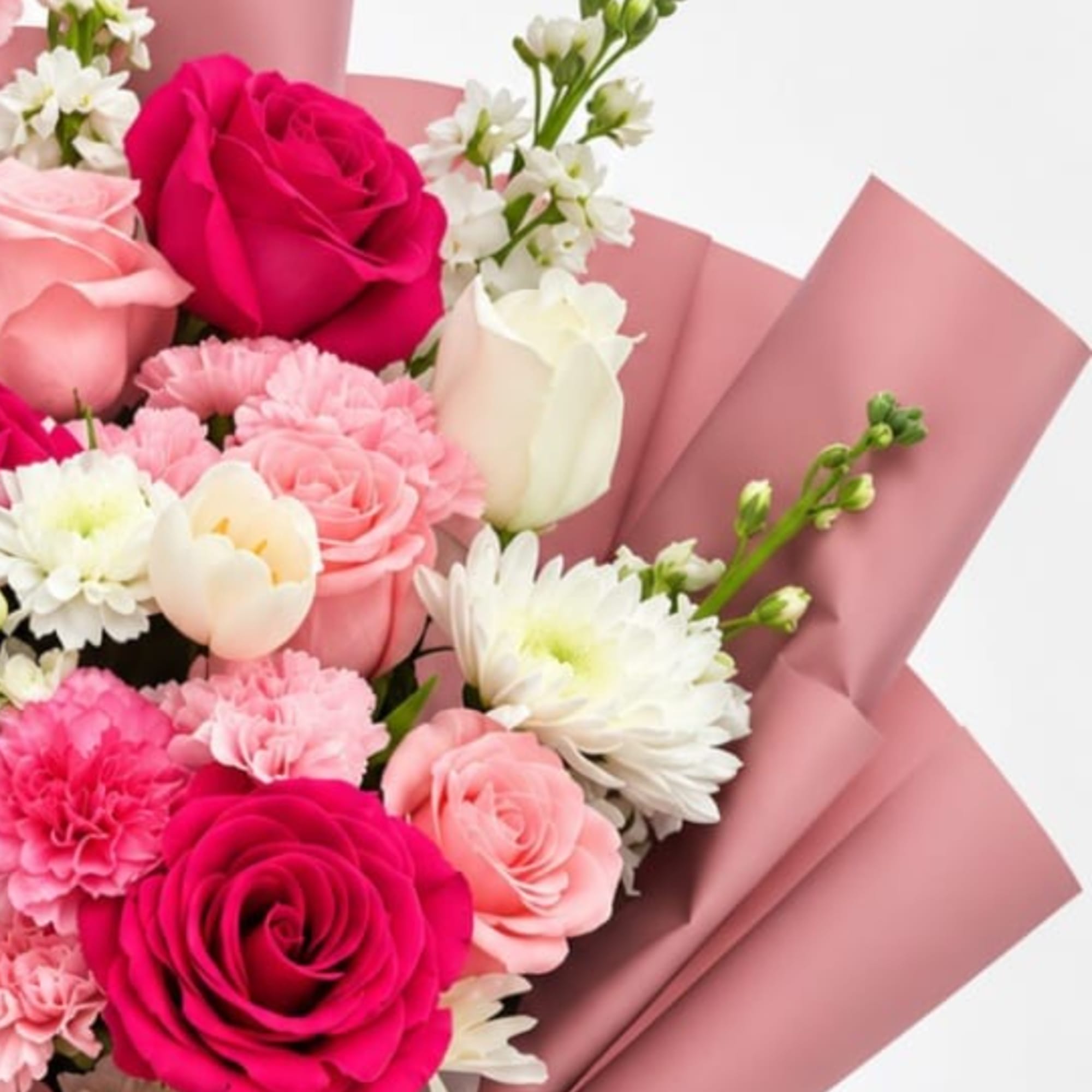 Pink and white bouquet with roses, carnations, and daisies wrapped in pink paper