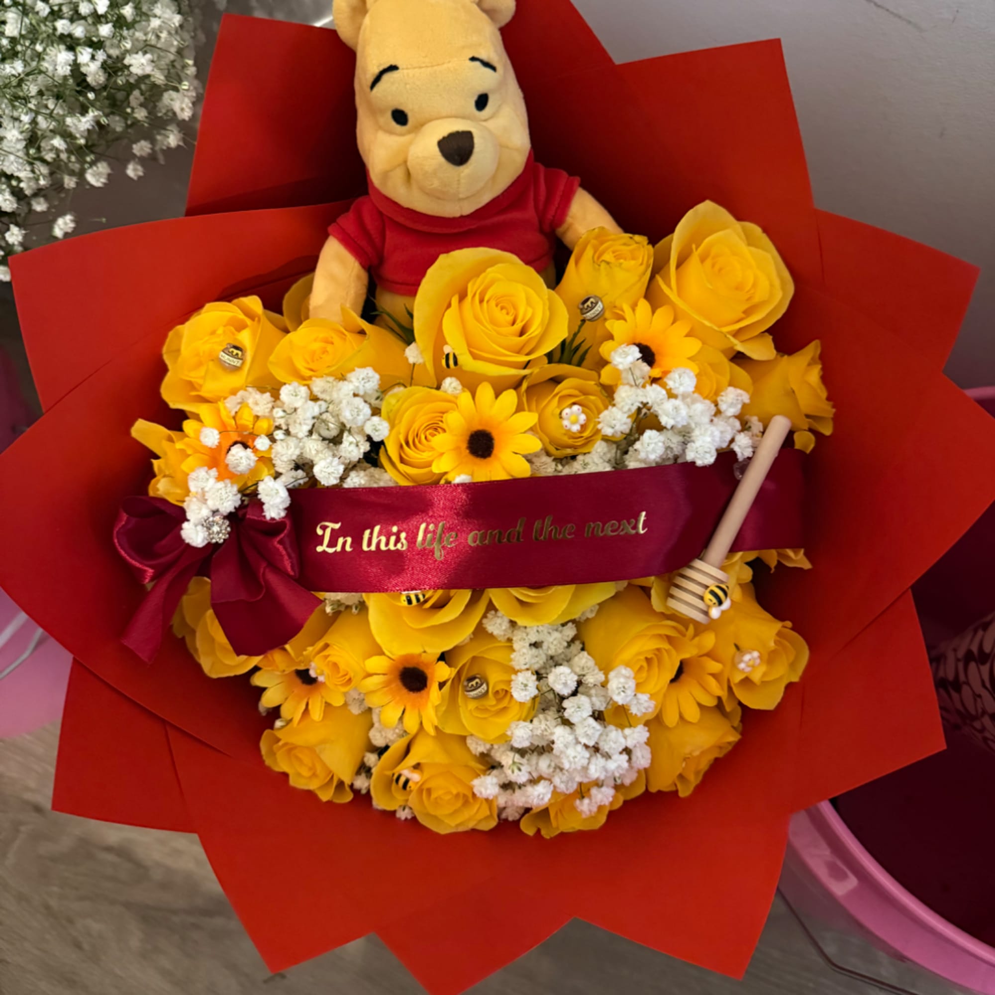Winnie the Pooh plush in a bouquet of yellow roses and daisies
