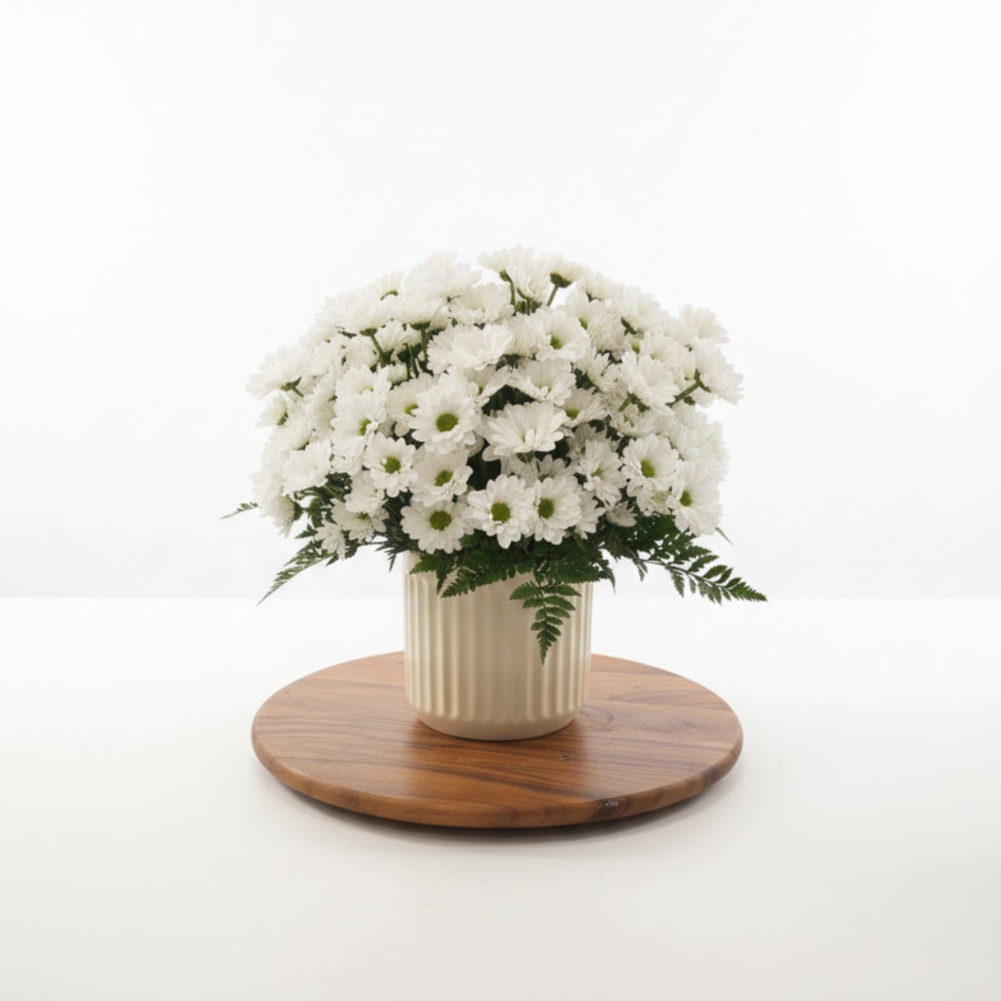 White daisy bouquet in a cream ribbed vase on a wooden tray