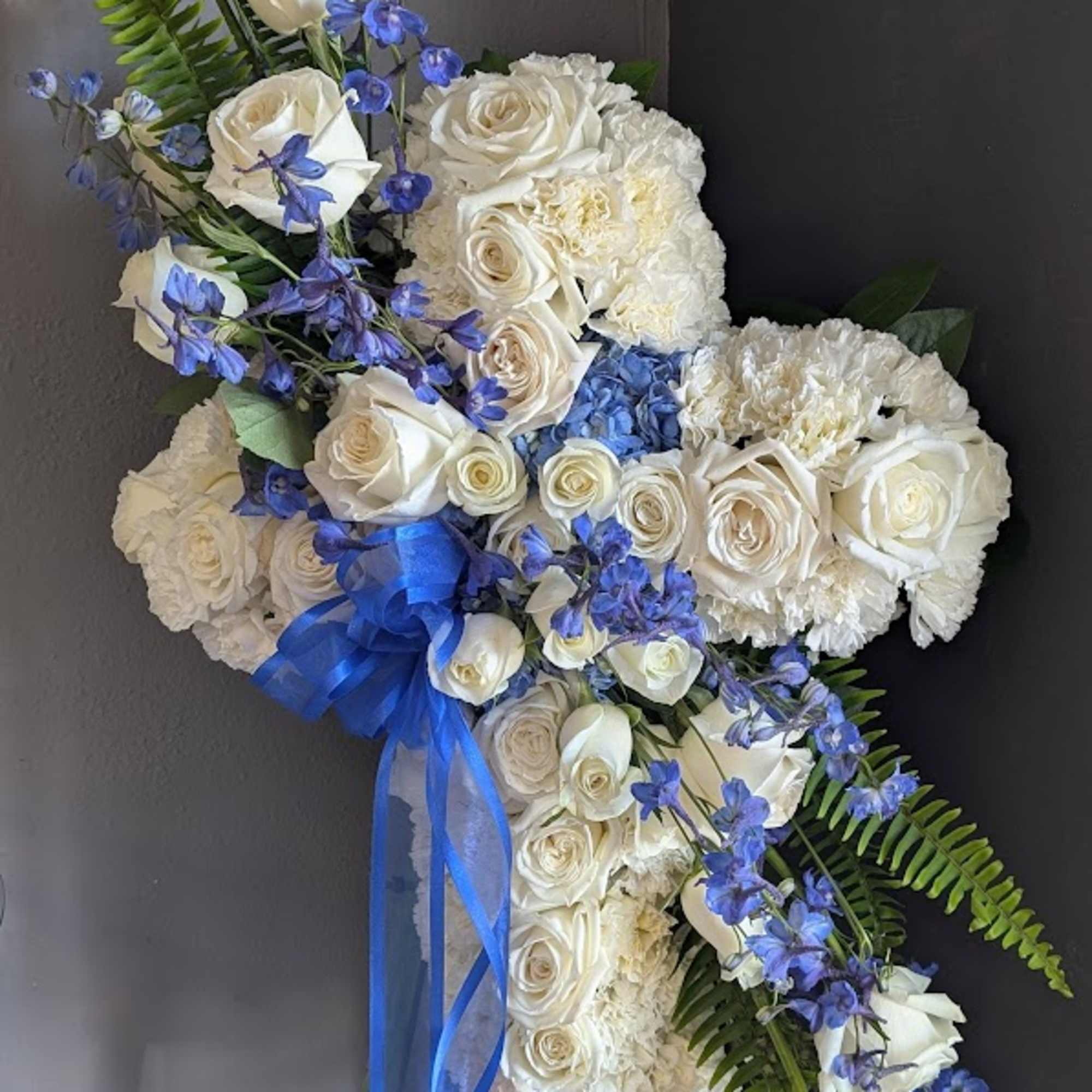 White rose and hydrangea floral spray with blue ribbon and blue flowers