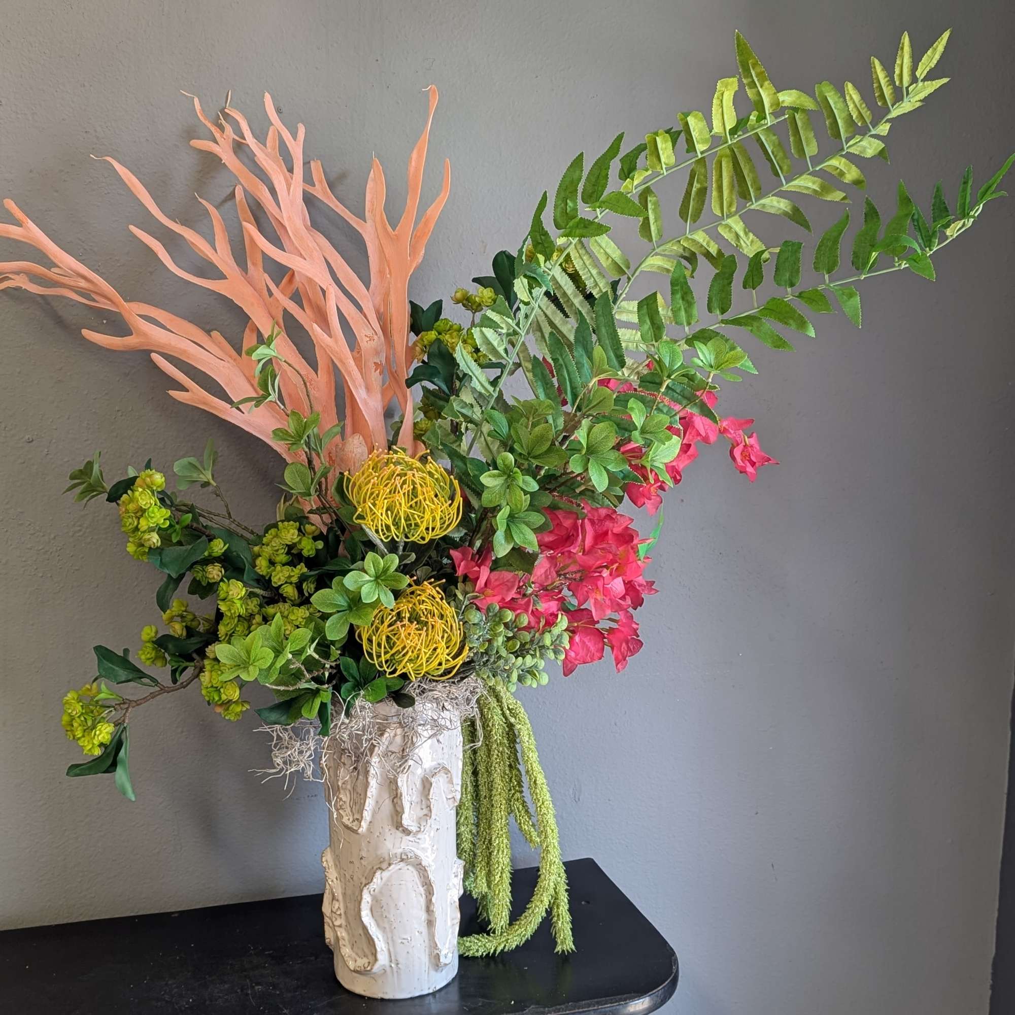 Tropical floral arrangement in a white vase with pink and yellow blooms