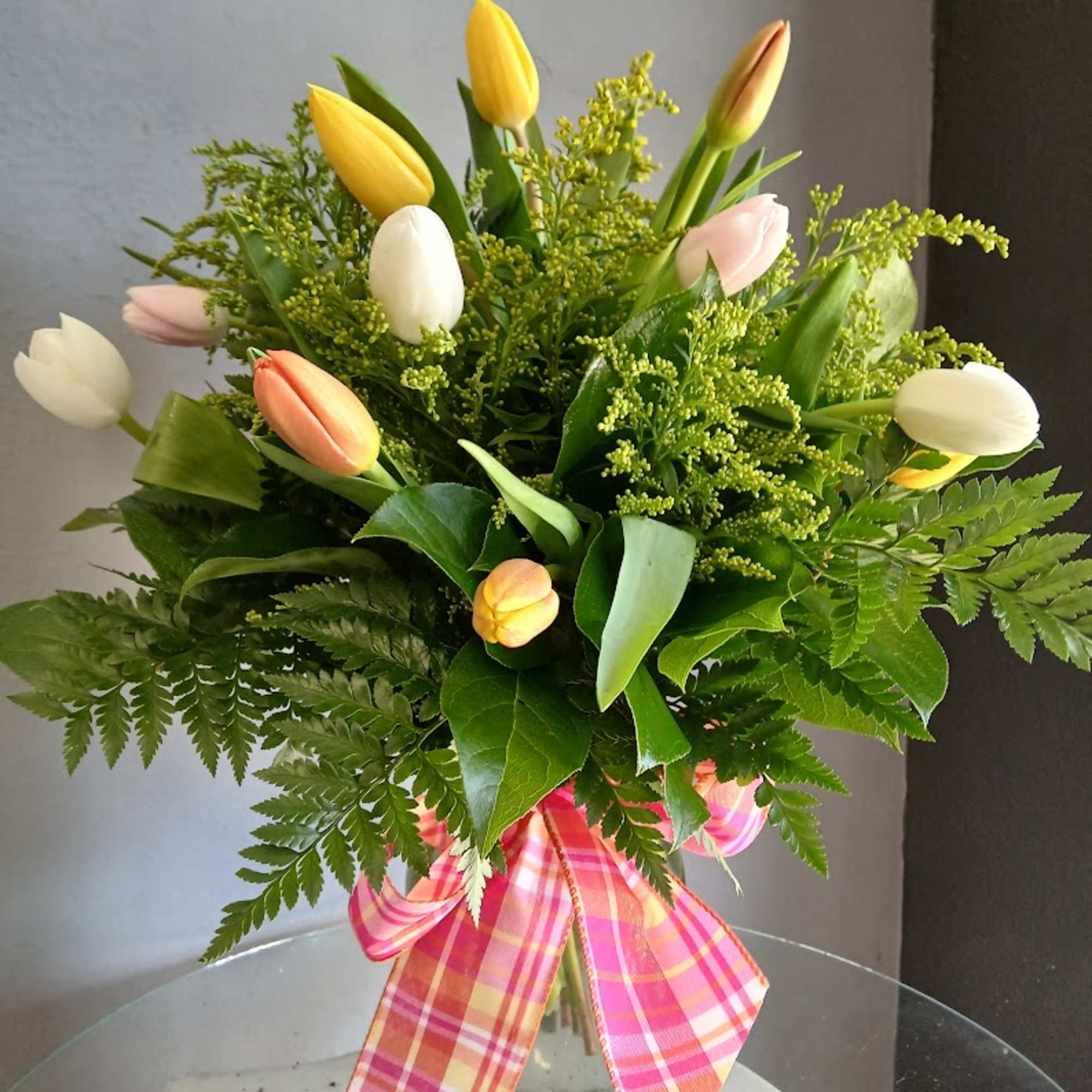 Mixed tulip bouquet in a glass vase with a pink plaid ribbon