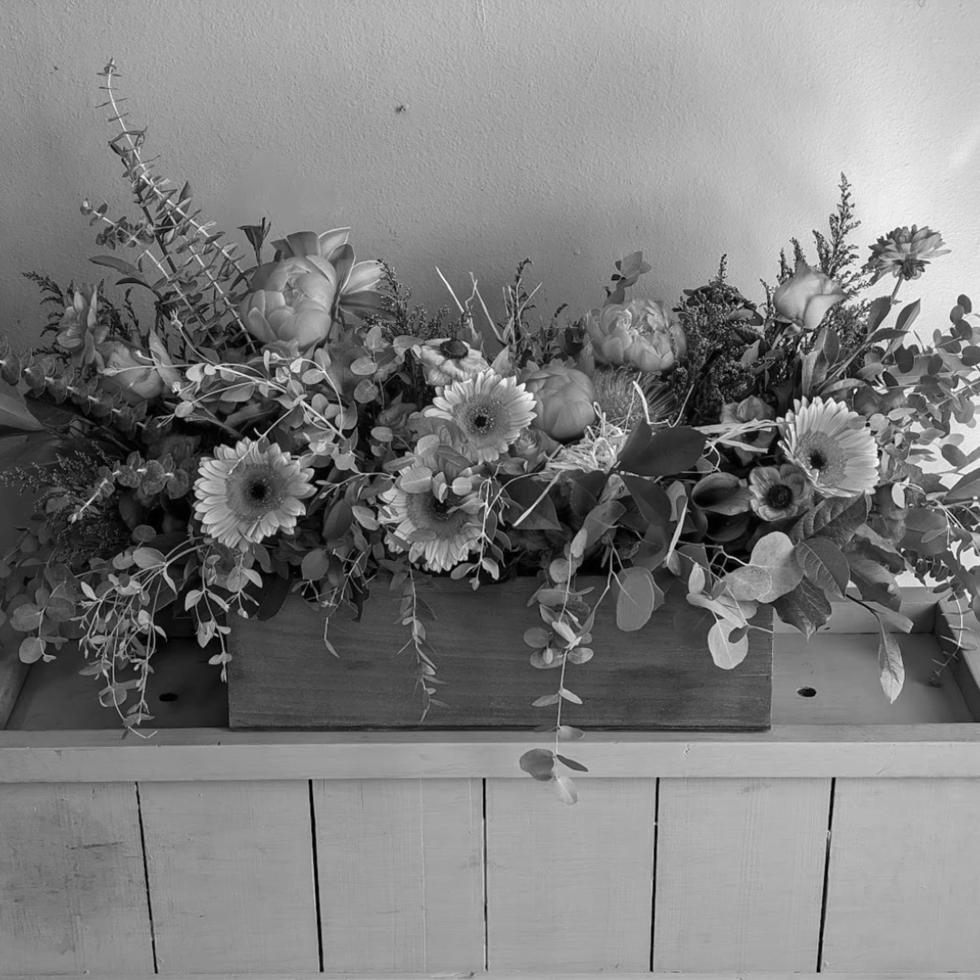 Low floral centerpiece with gerbera daisies and mixed greenery in a wooden box