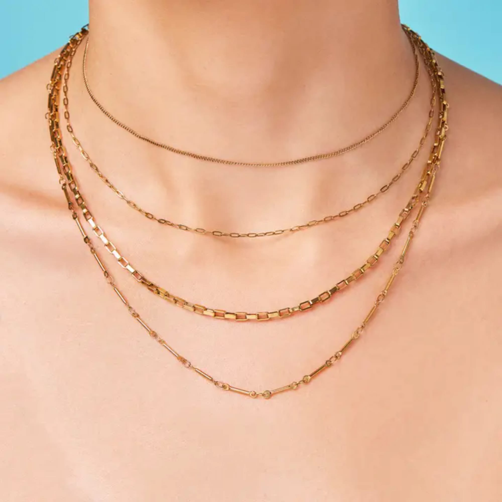 Layered gold necklaces on a bare neck and shoulders