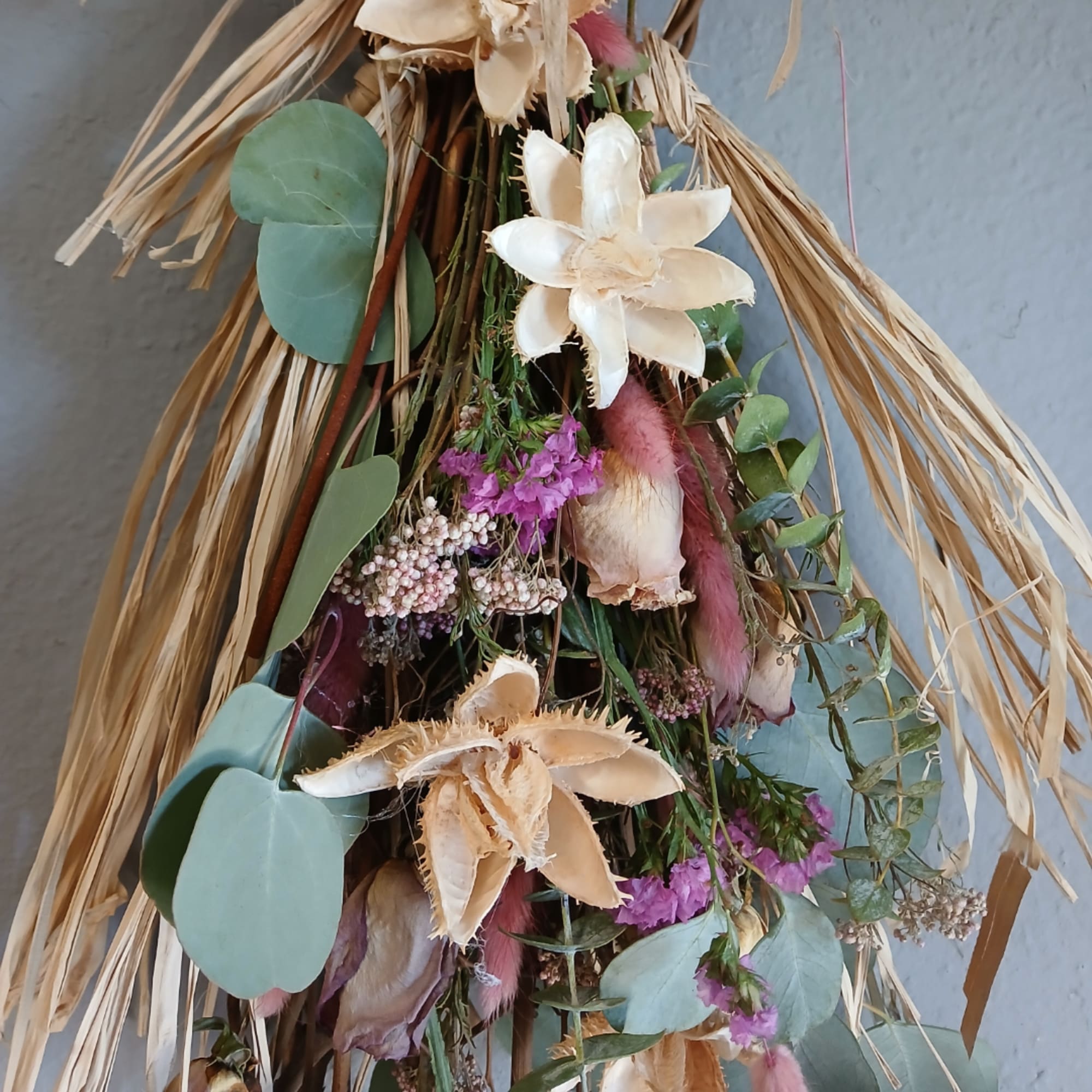 Dried floral hanging arrangement with cream flowers, pink accents, and eucalyptus