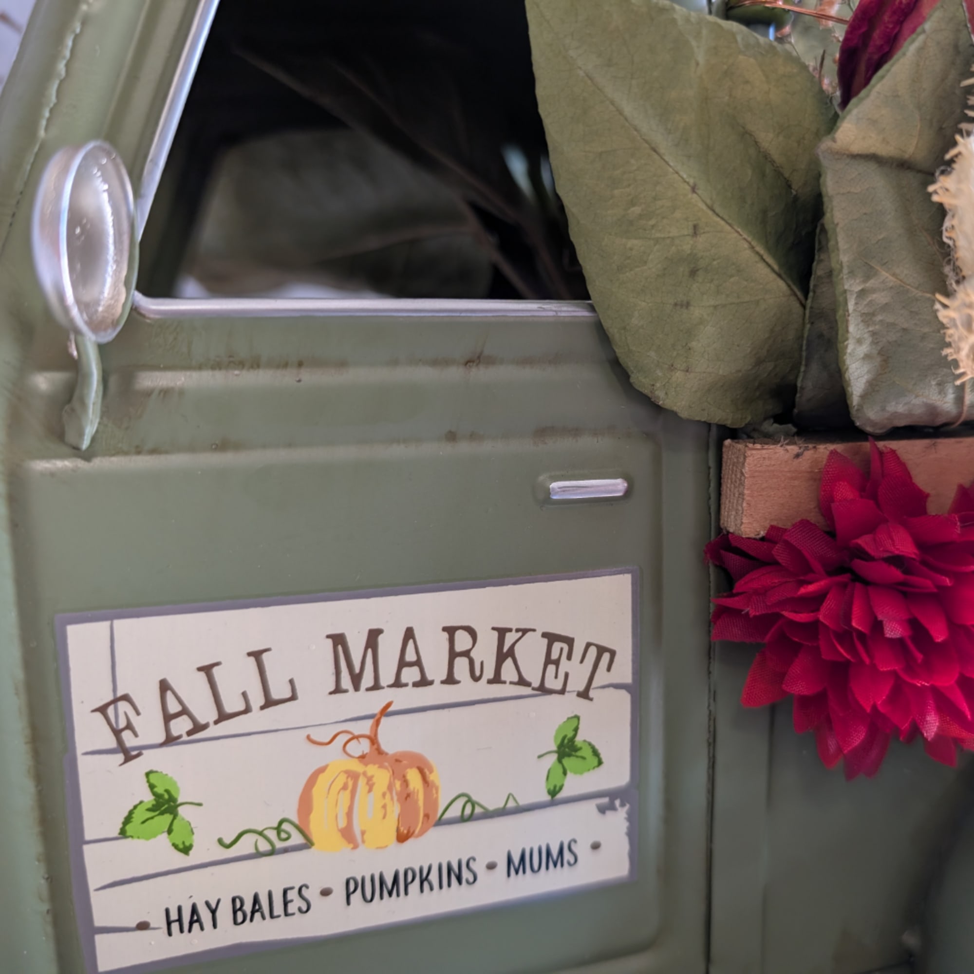Fall market sign on a green metal container with a red flower decoration