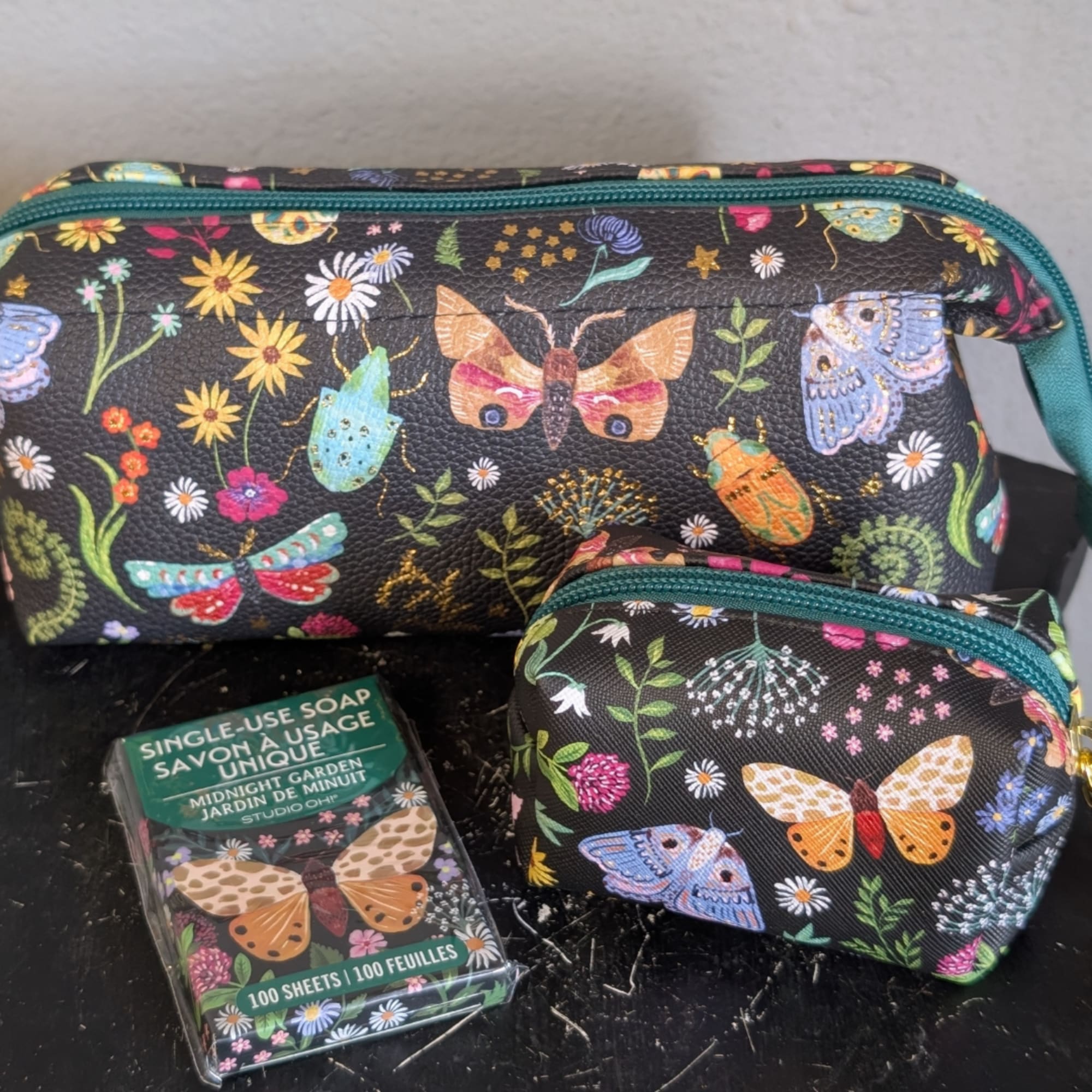 Butterfly-print cosmetic bags with a matching soap pack on a dark surface.