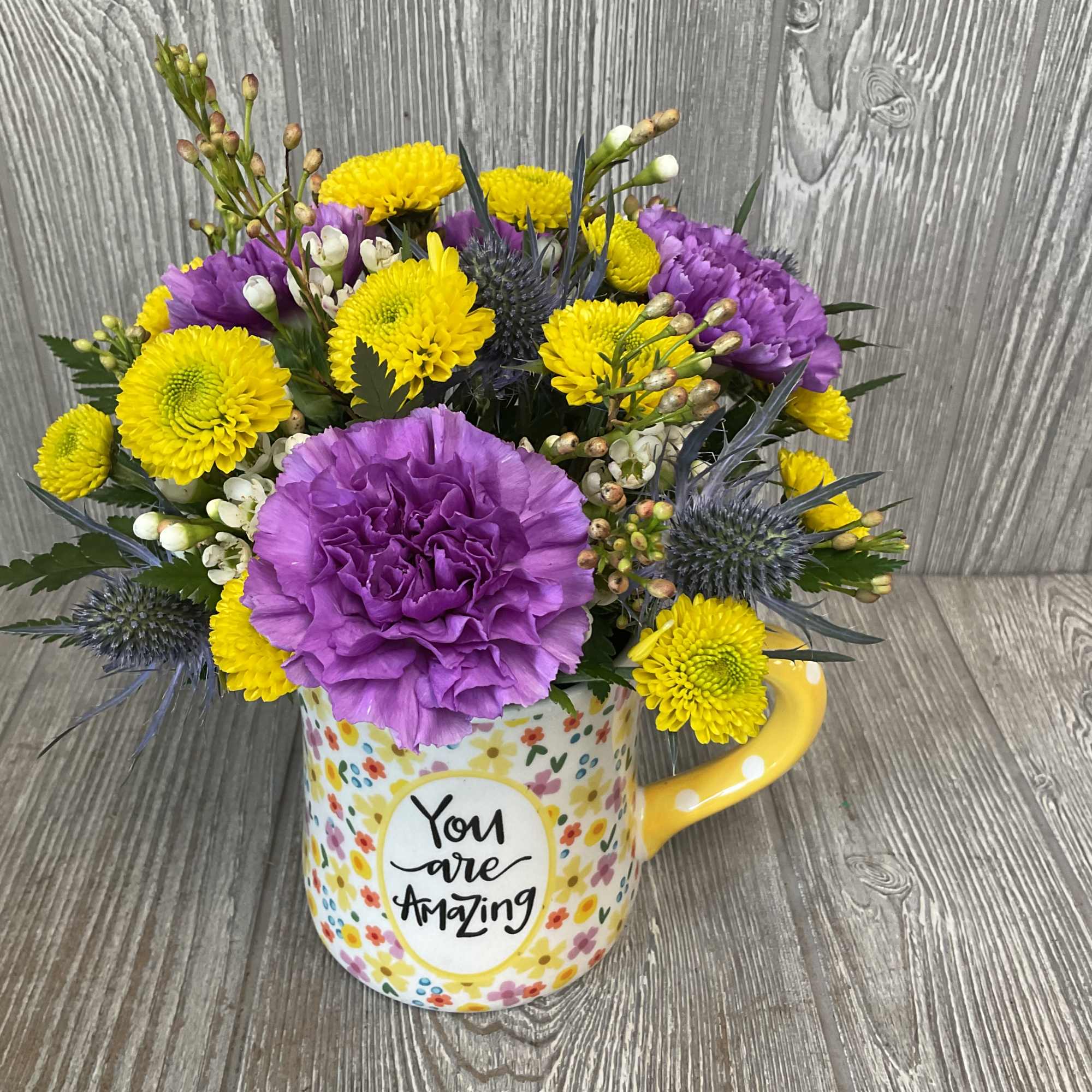 Bouquet of yellow and purple flowers in a mug with "You are Amazing" text