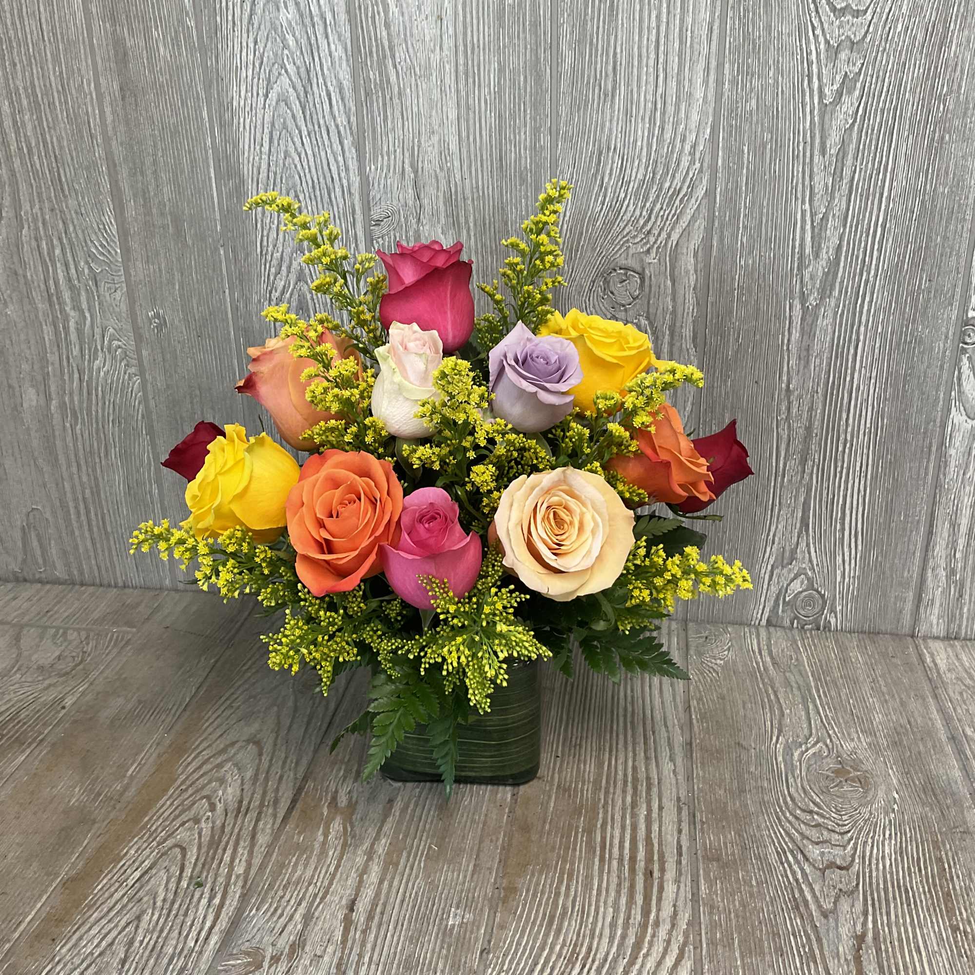 Mixed roses in a green square vase with yellow filler flowers