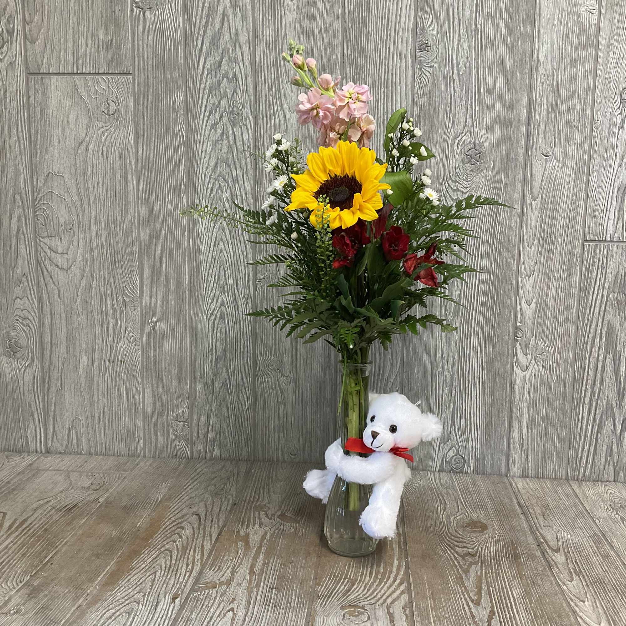 Sunflower bouquet in a glass vase with a white teddy bear
