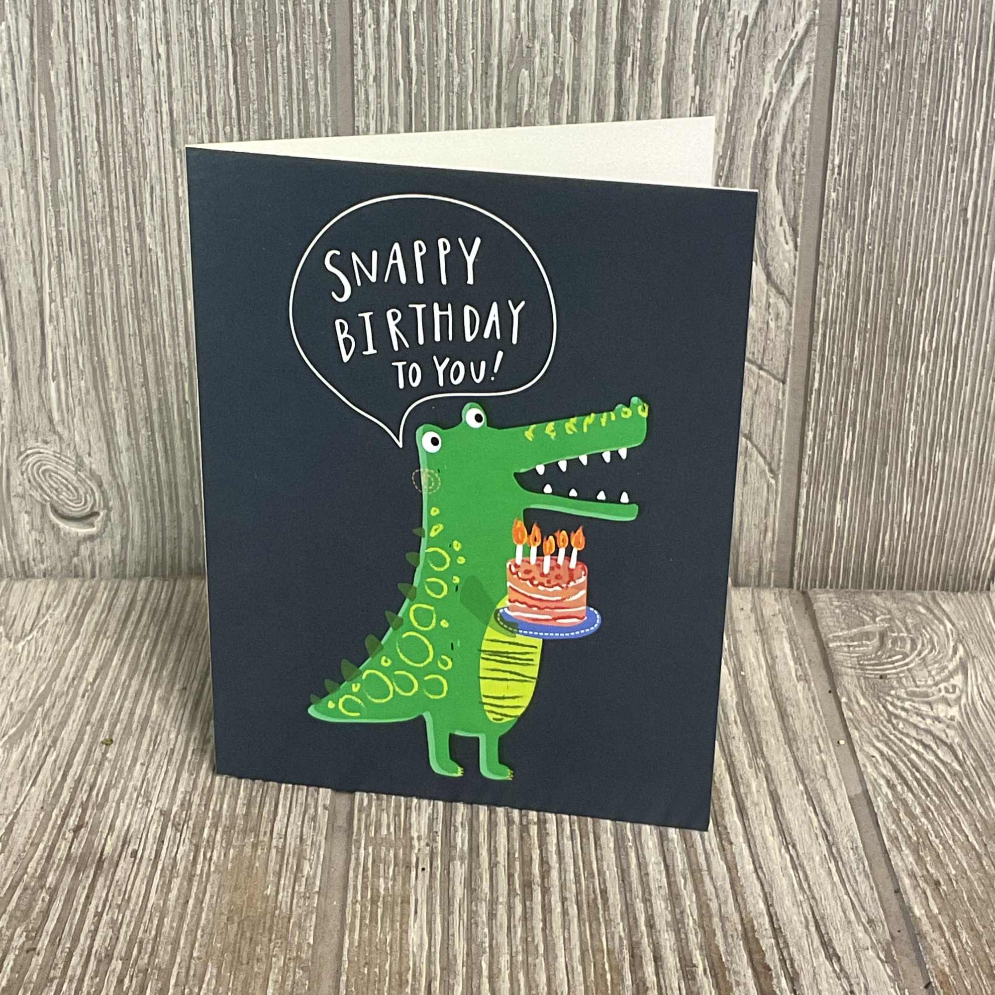 Birthday card with a green cartoon crocodile holding a cake