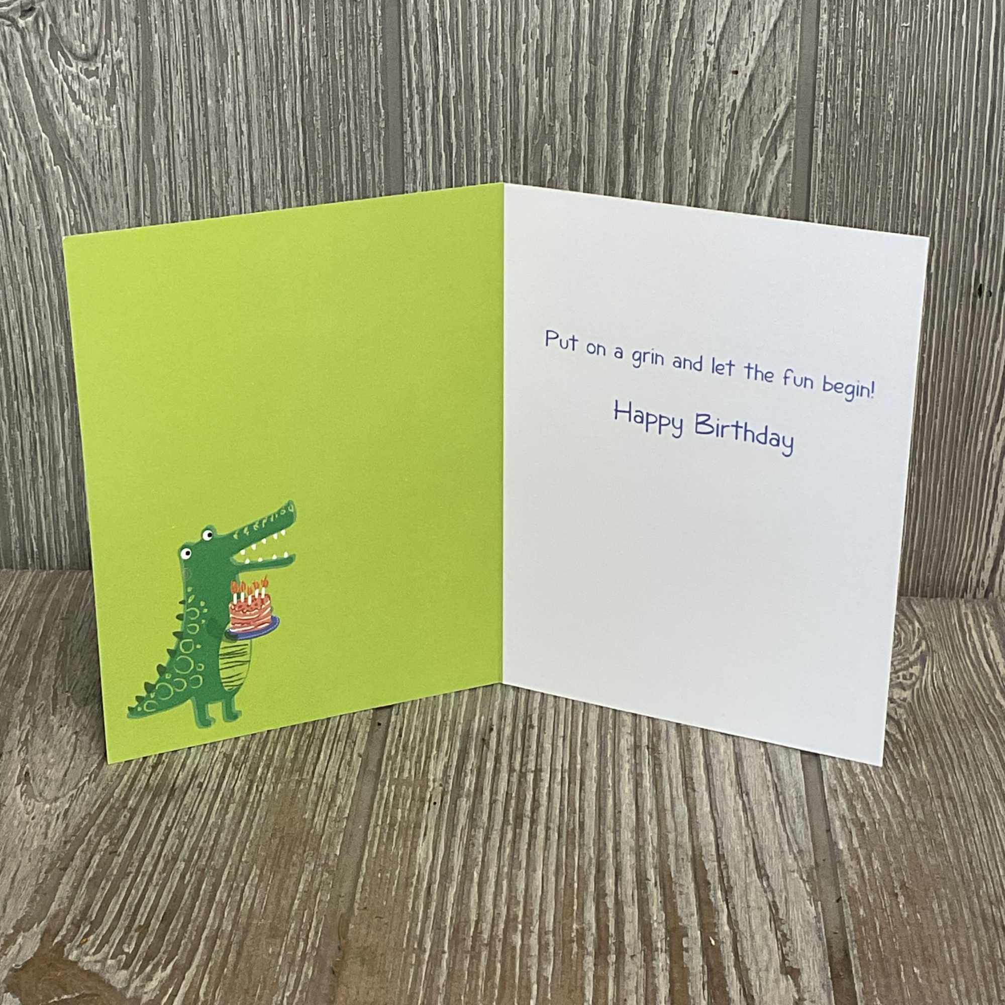 Birthday card with a cartoon crocodile holding a cake
