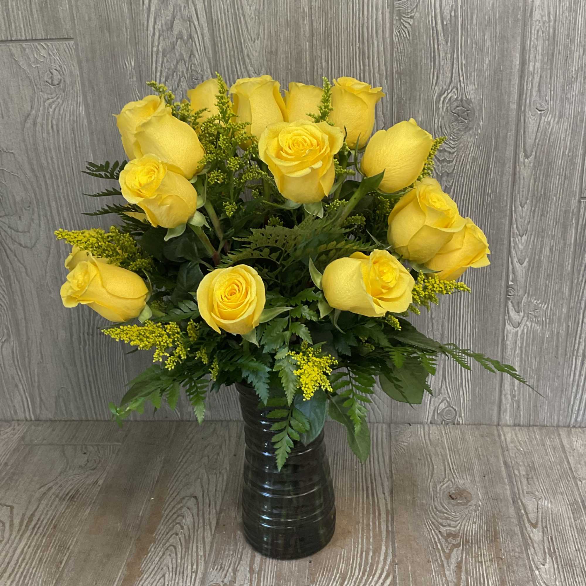 Yellow roses arranged in a dark glass vase