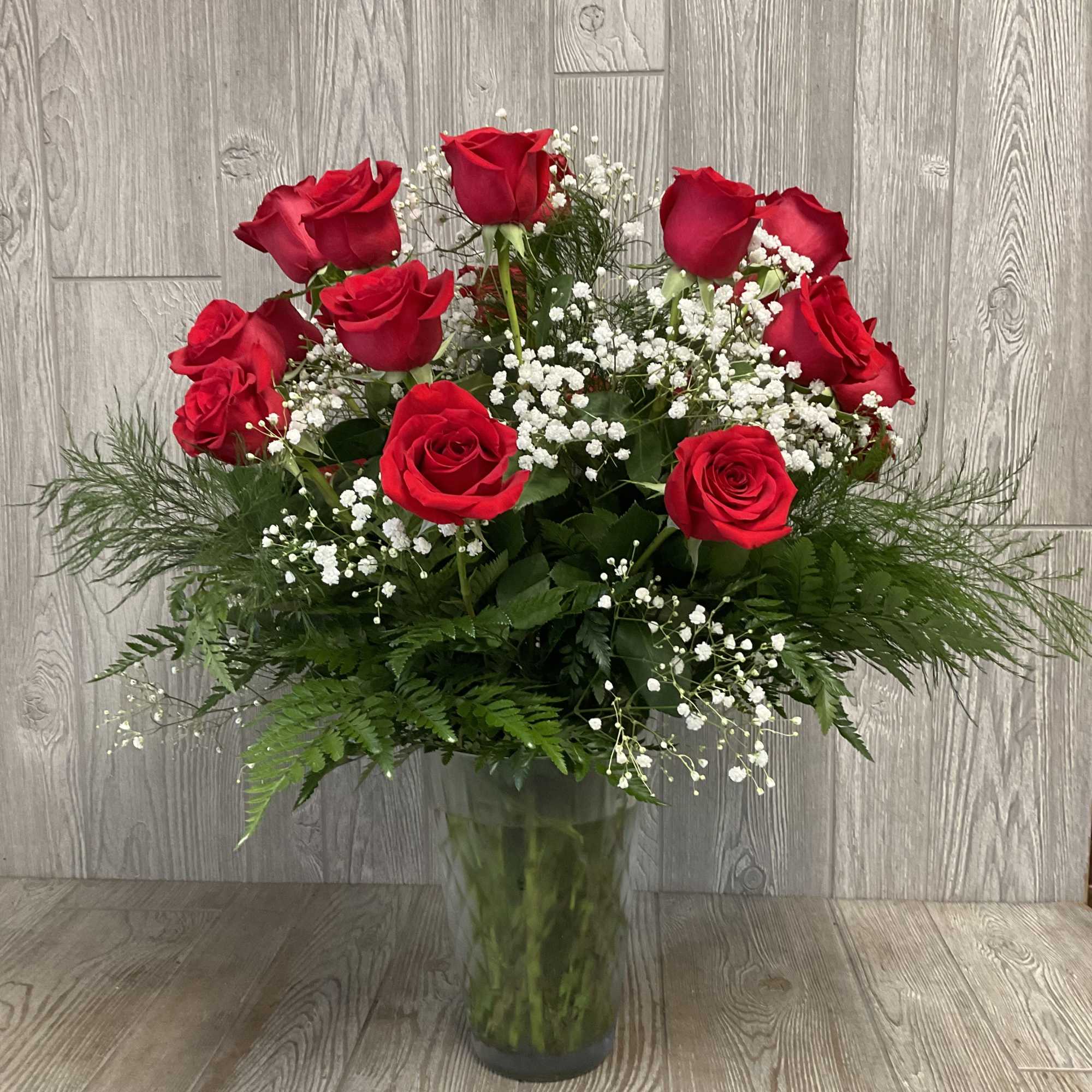 Red roses with white baby's breath in a clear glass vase