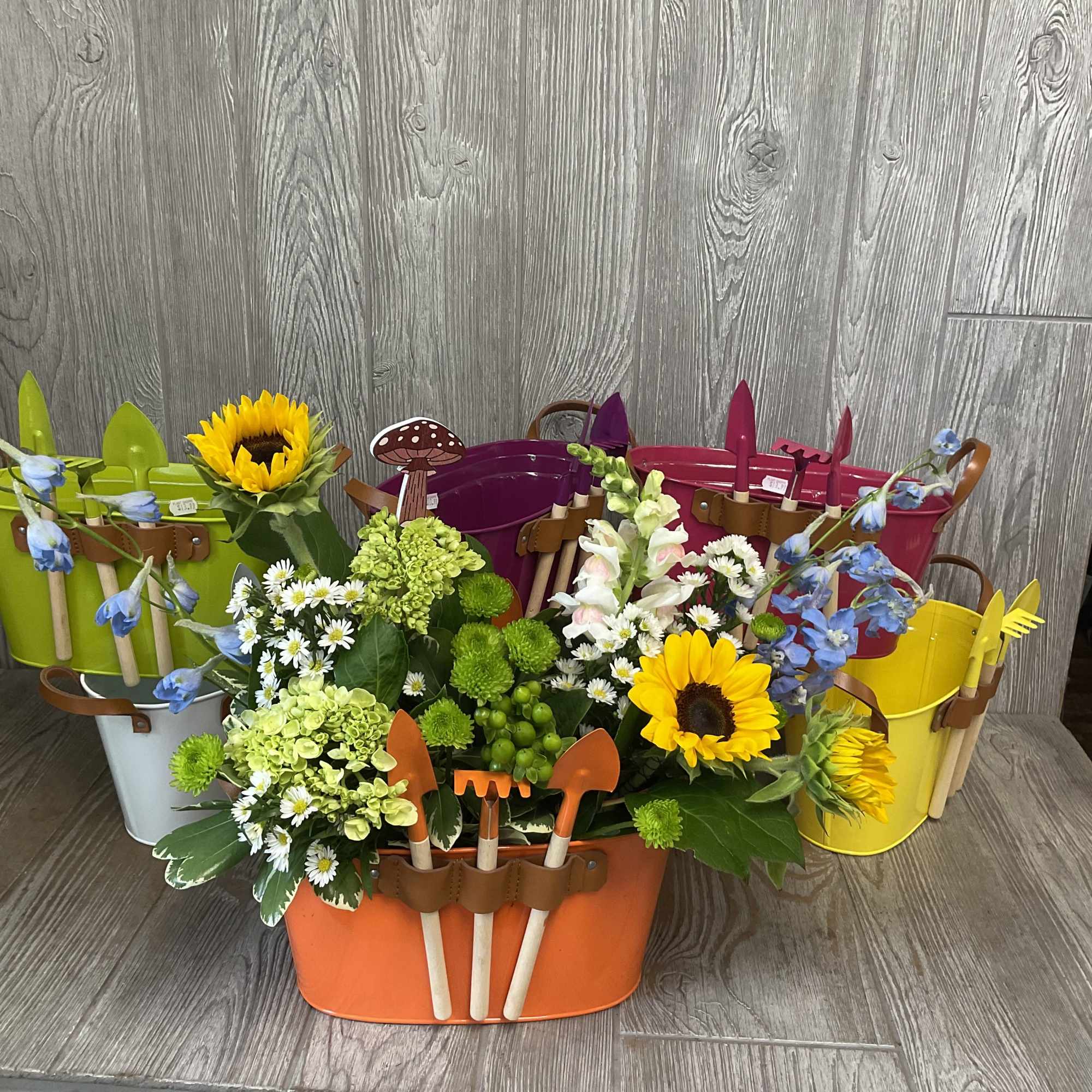 Colorful flower arrangement in small garden buckets with toy tools