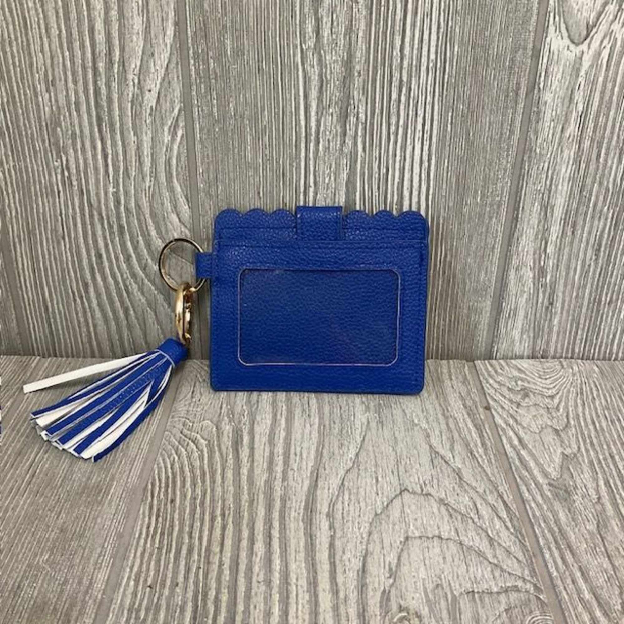 Blue card holder with a tassel keychain on a wood floor