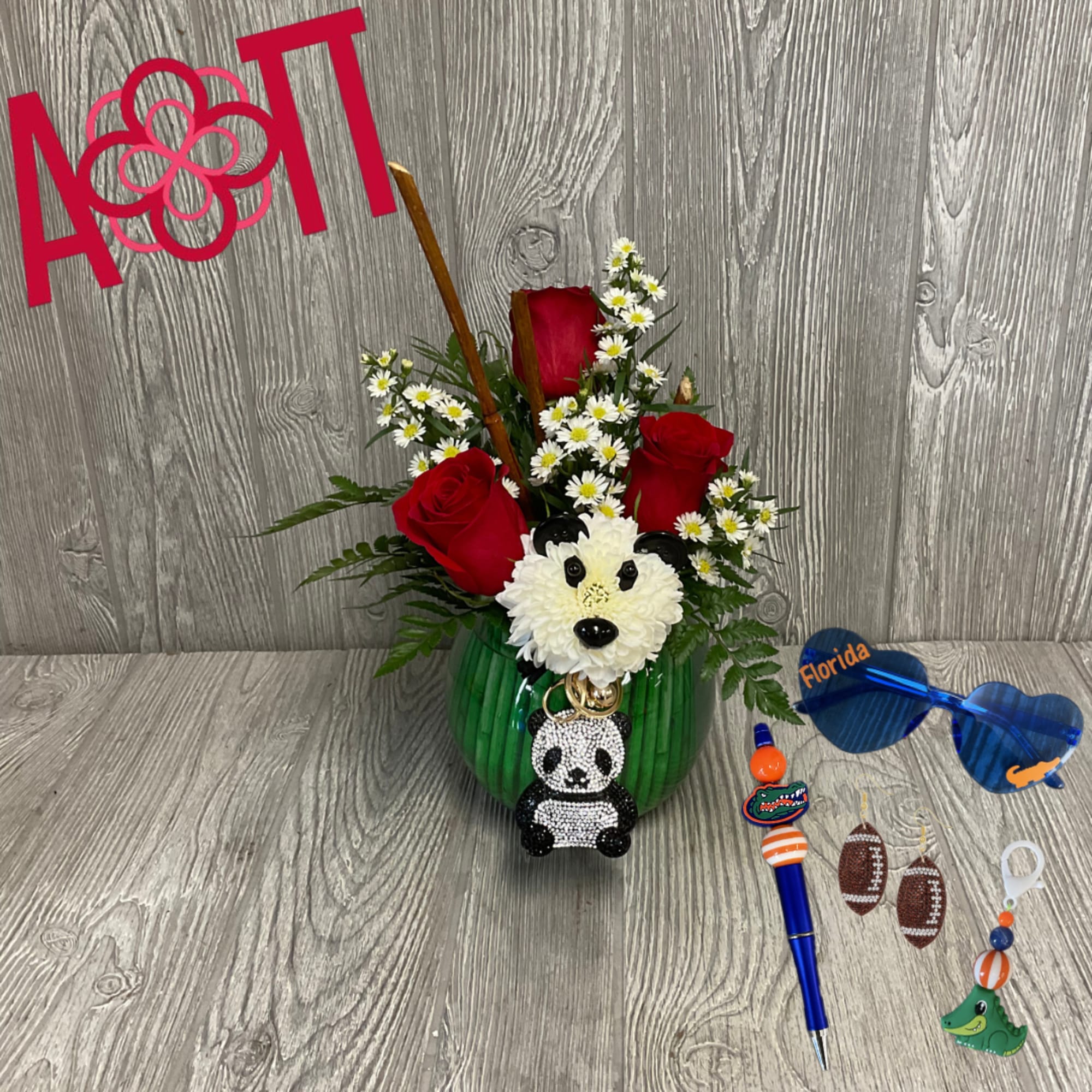 Red roses and white daisies in a green vase with a panda charm