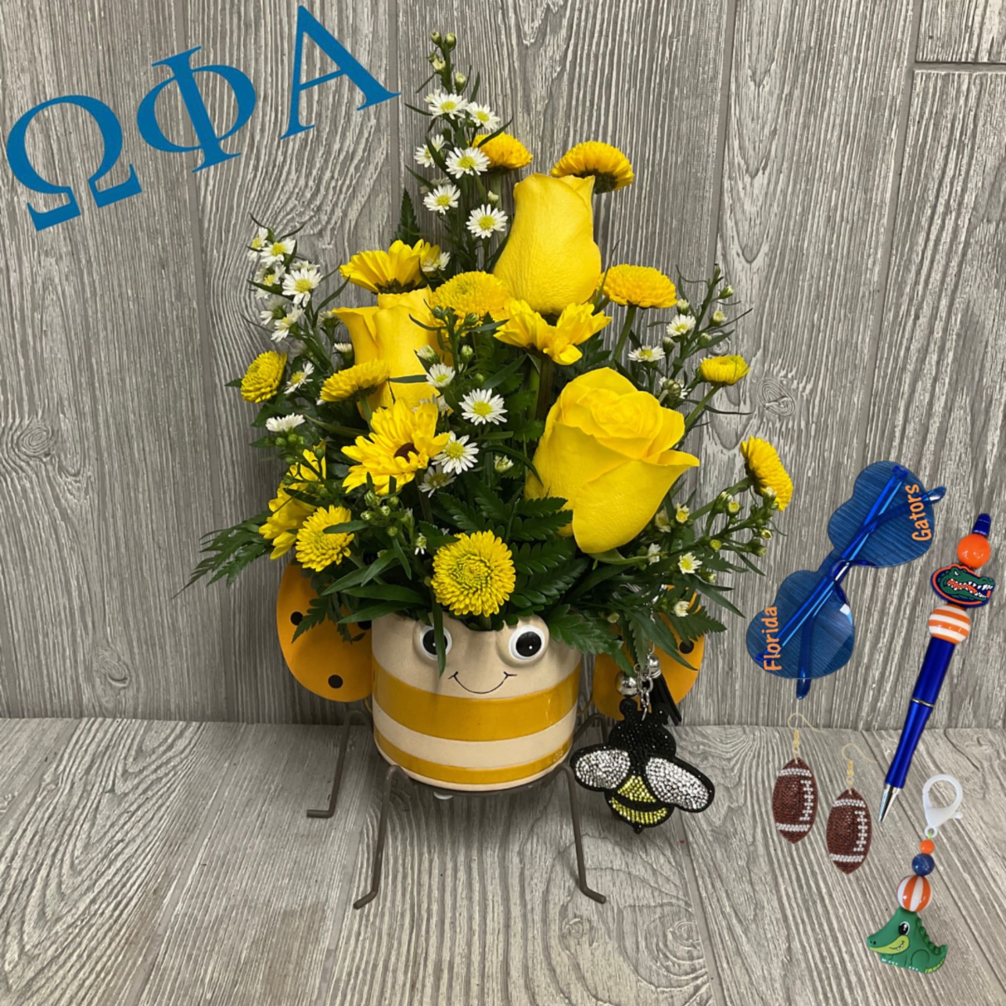 Yellow roses and daisies in a striped bee pot with sports-themed accessories